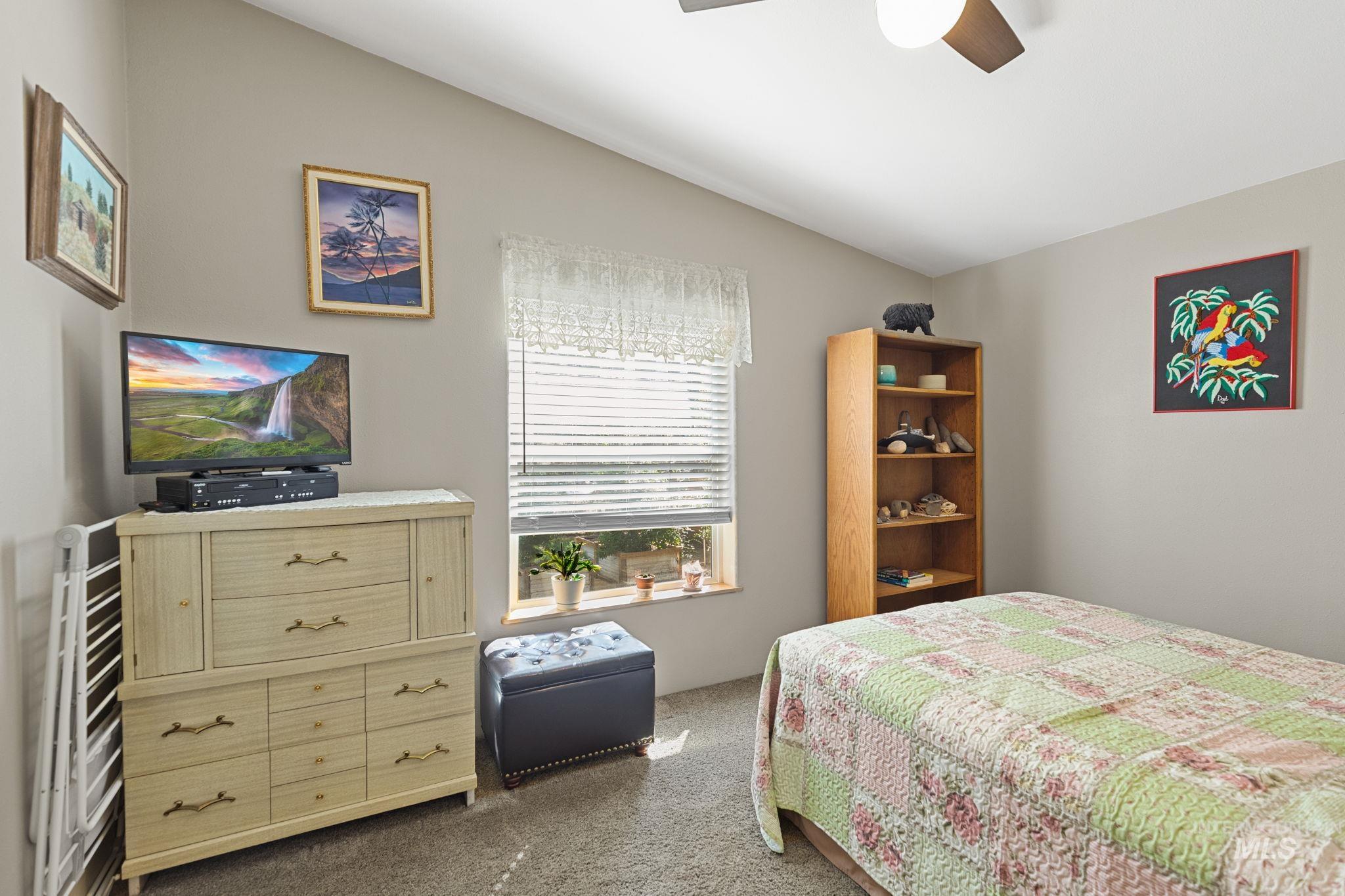 Bedroom with lofted ceiling, dark colored carpet, and a ceiling fan