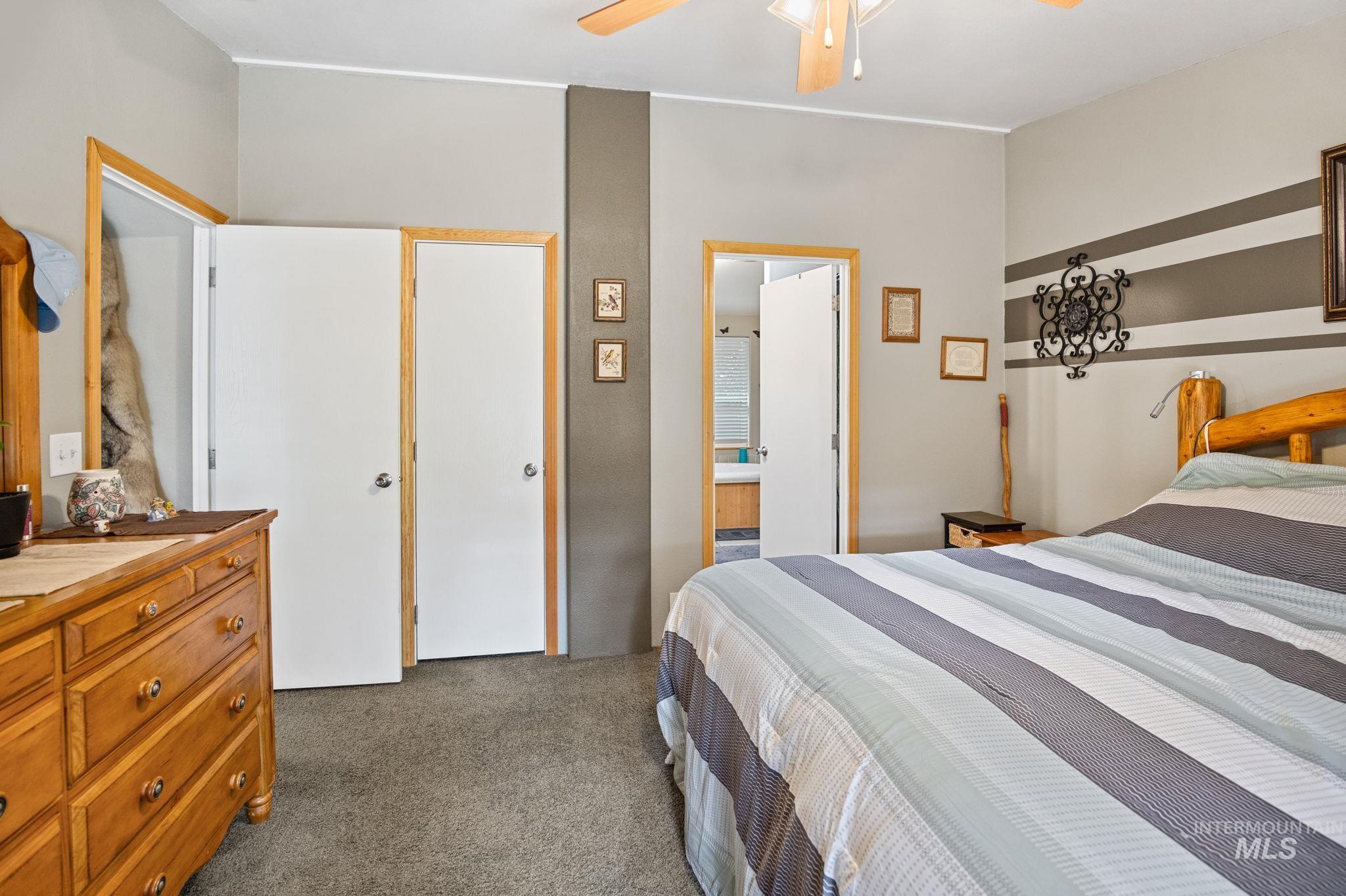 Carpeted bedroom with a ceiling fan and ensuite bath