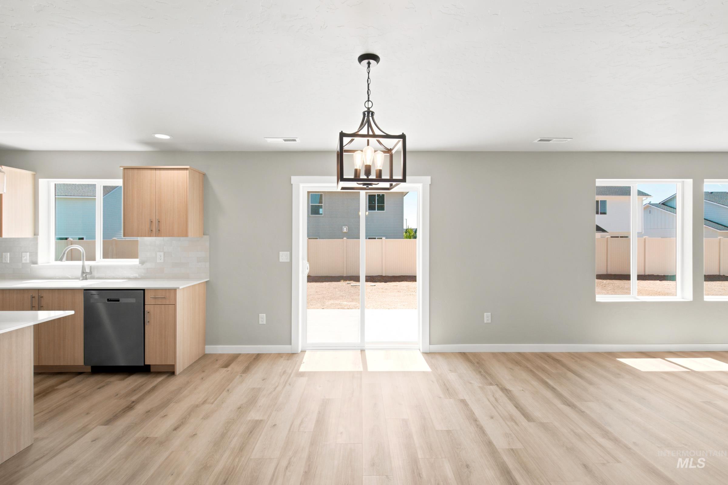 Open-concept living area featuring wood-finish flooring, a contemporary chandelier, and light gray wall tones