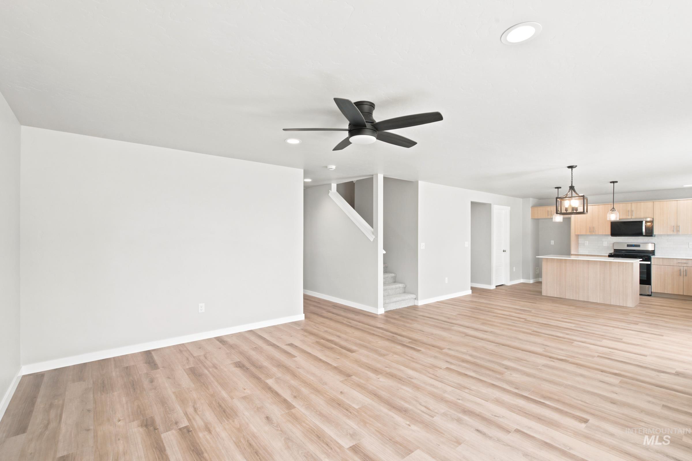 Spacious living area featuring wood-finish flooring, a modern ceiling fan, recessed lighting, and a neutral color palette