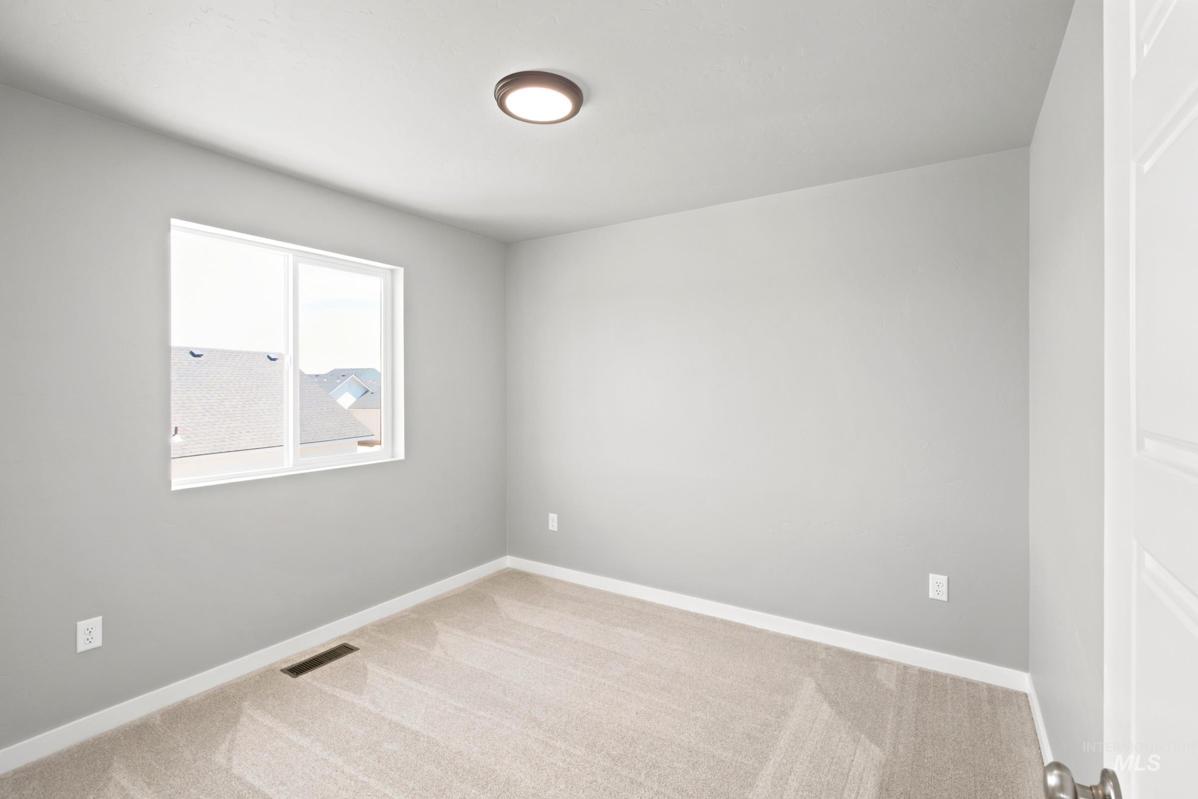 Carpeted room featuring a white-framed window, flush-mount ceiling light, white baseboards, and neutral wall paint