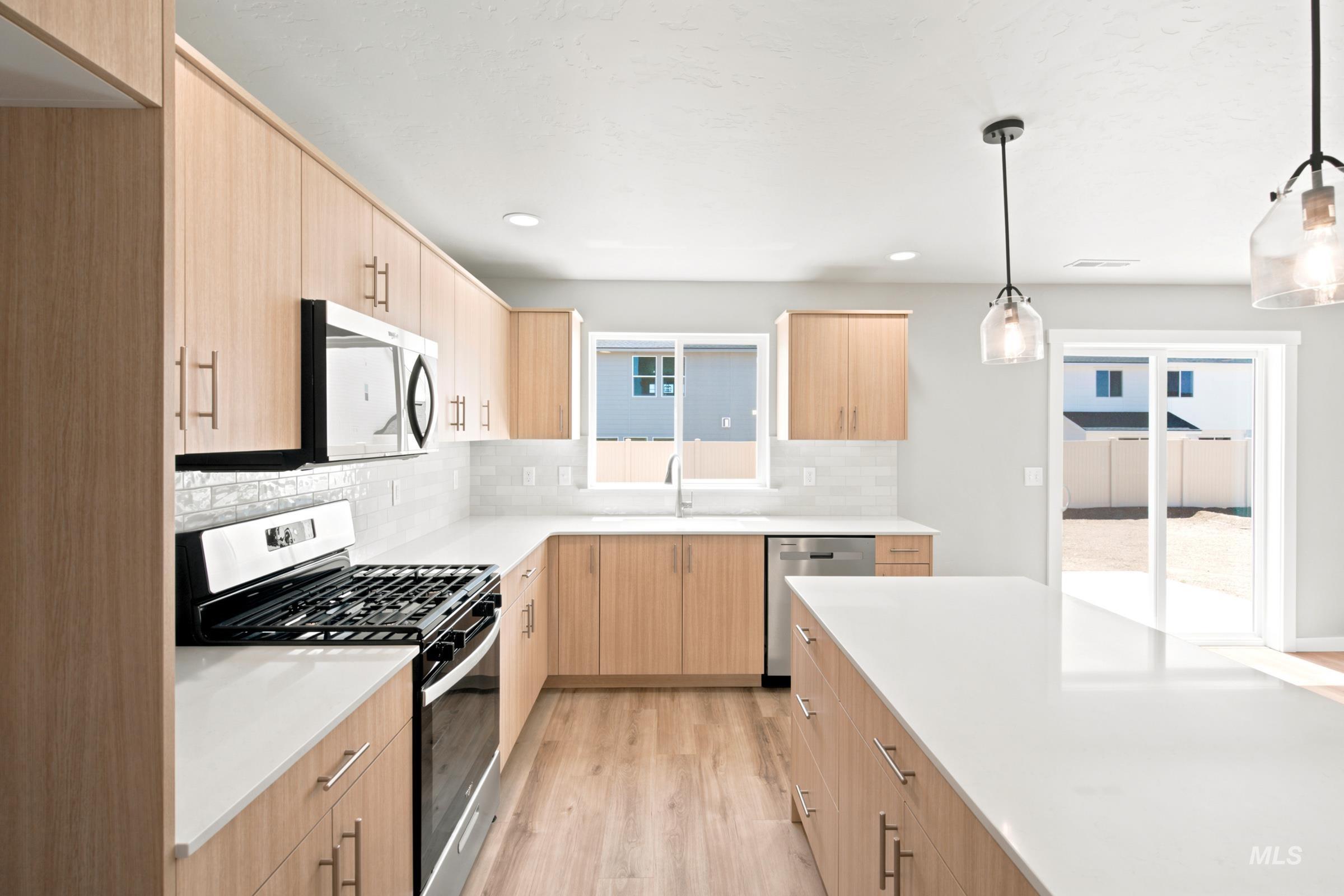 Modern kitchen featuring wood-finish cabinetry, white countertops, and stainless steel appliances