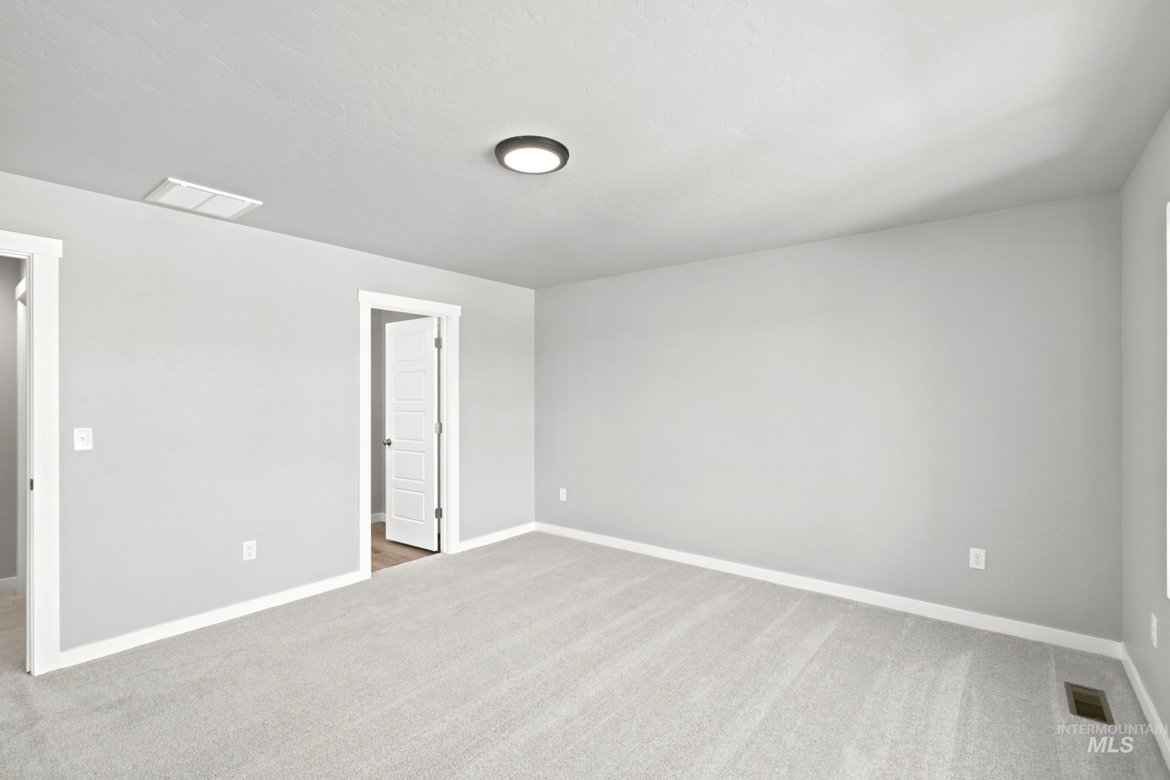 Spacious room featuring light gray walls, plush gray carpeting, white trim, and a contemporary ceiling light fixture