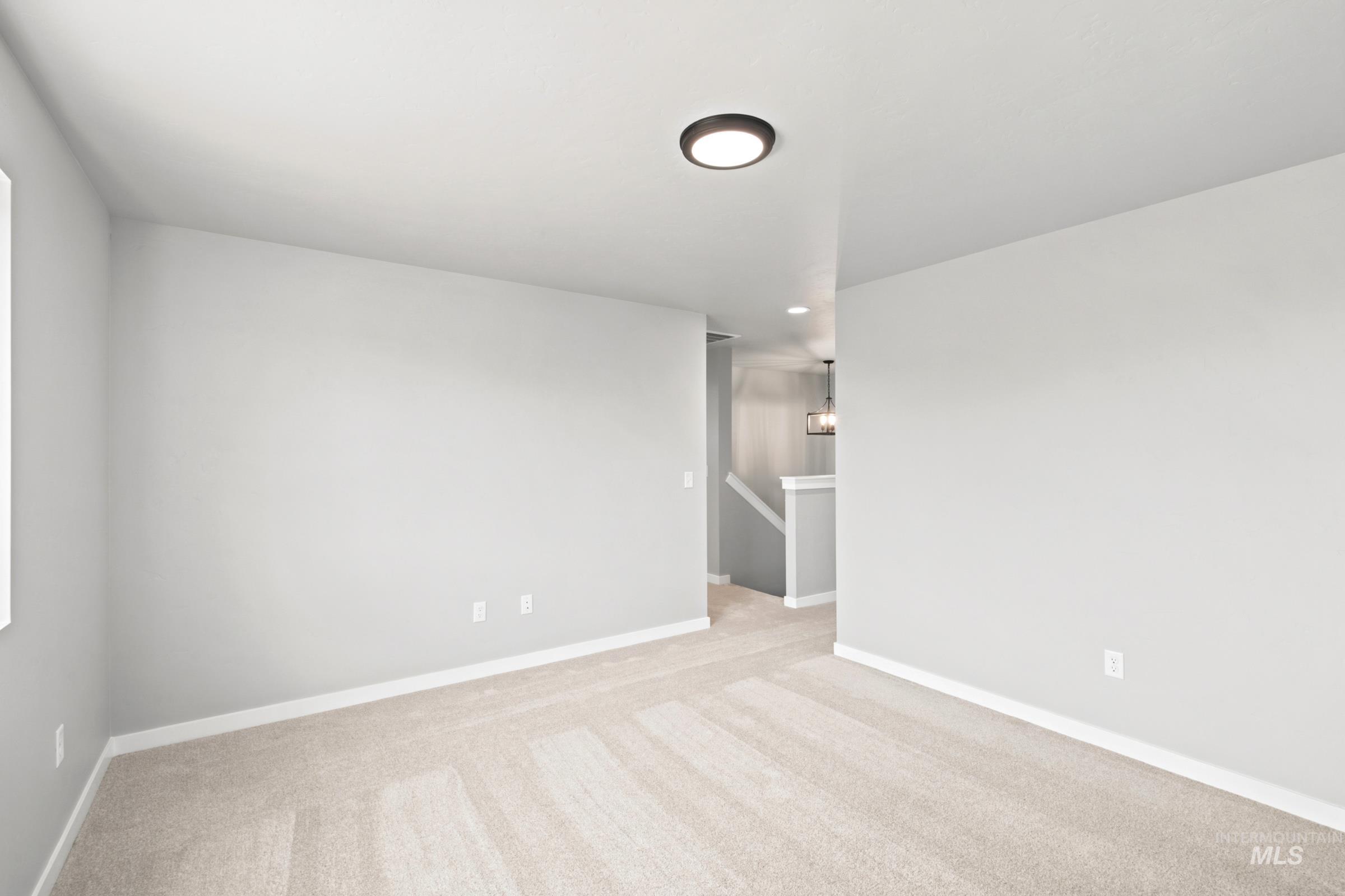 Spacious room featuring neutral carpeting and light gray wall paint