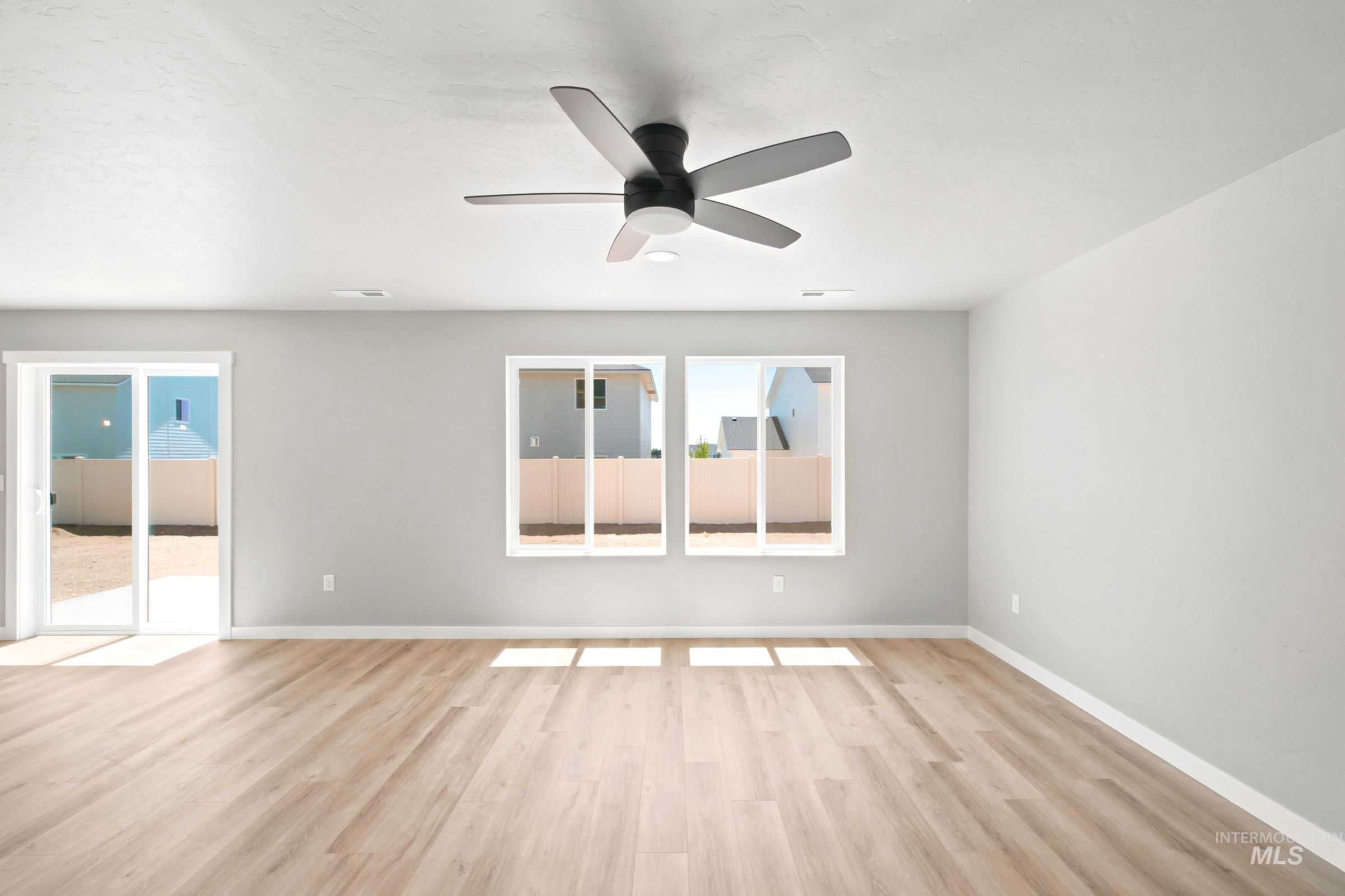 Spacious room featuring light wood-finish flooring and a modern ceiling fan