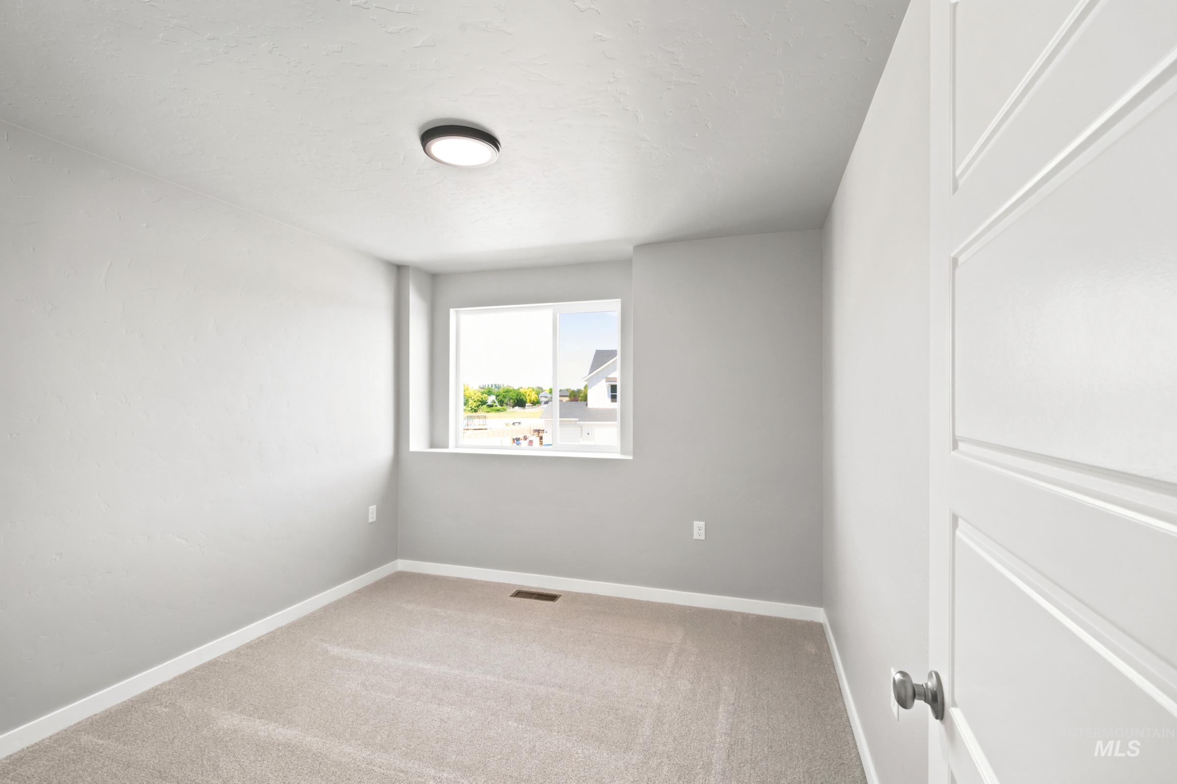 Light gray interior space featuring neutral carpeting and a single window