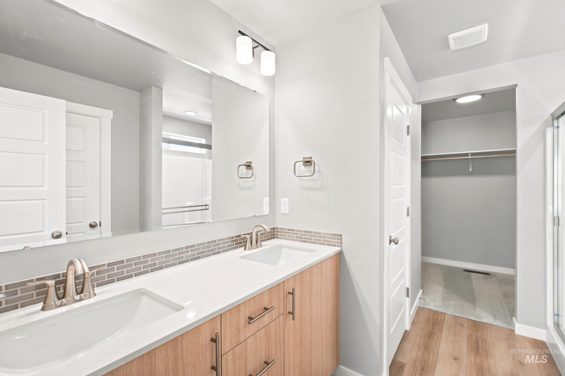 Bathroom featuring a dual vanity with light wood-finish cabinetry, white countertops, and brushed nickel fixtures