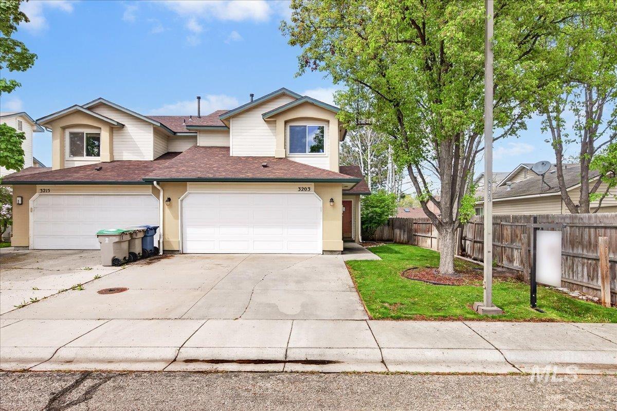 Traditional-style house featuring roof with shingles, driveway, and a garage