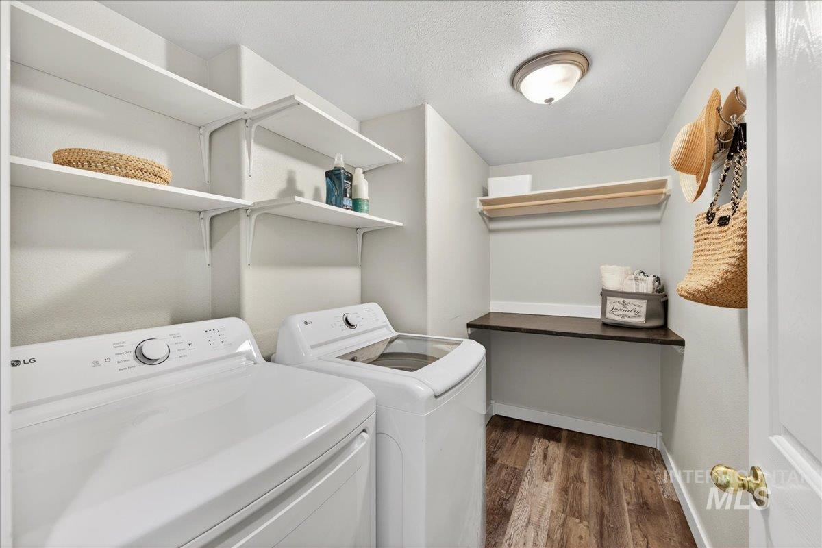 Laundry room featuring dark wood-style flooring, separate washer and dryer, and a textured ceiling