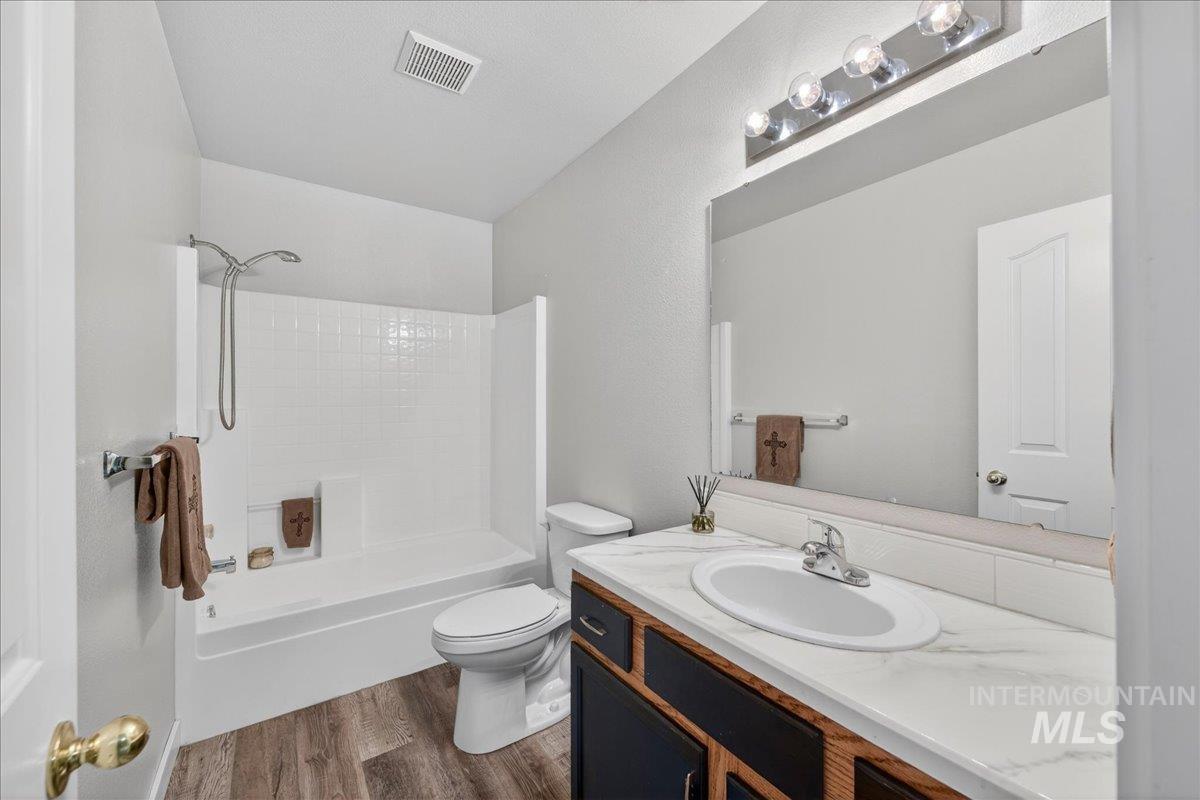 Bathroom featuring vanity, shower / tub combination, and dark wood-type flooring