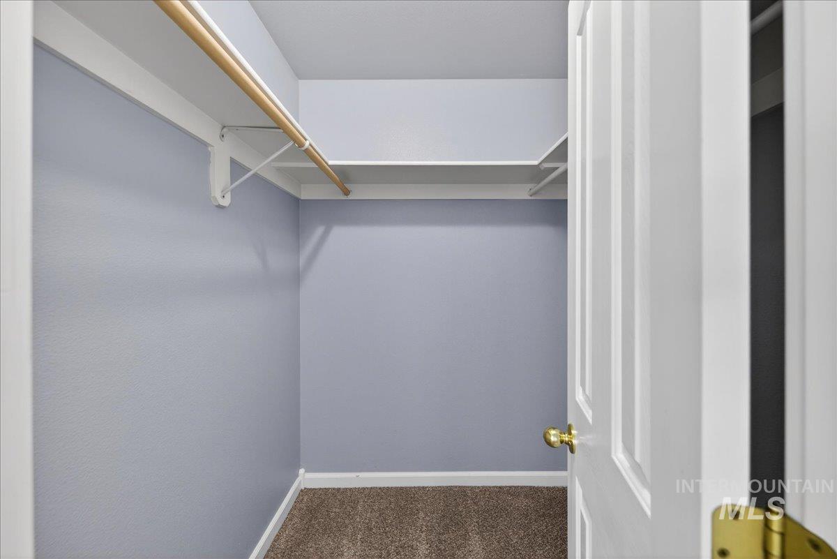 Walk in closet featuring dark colored carpet