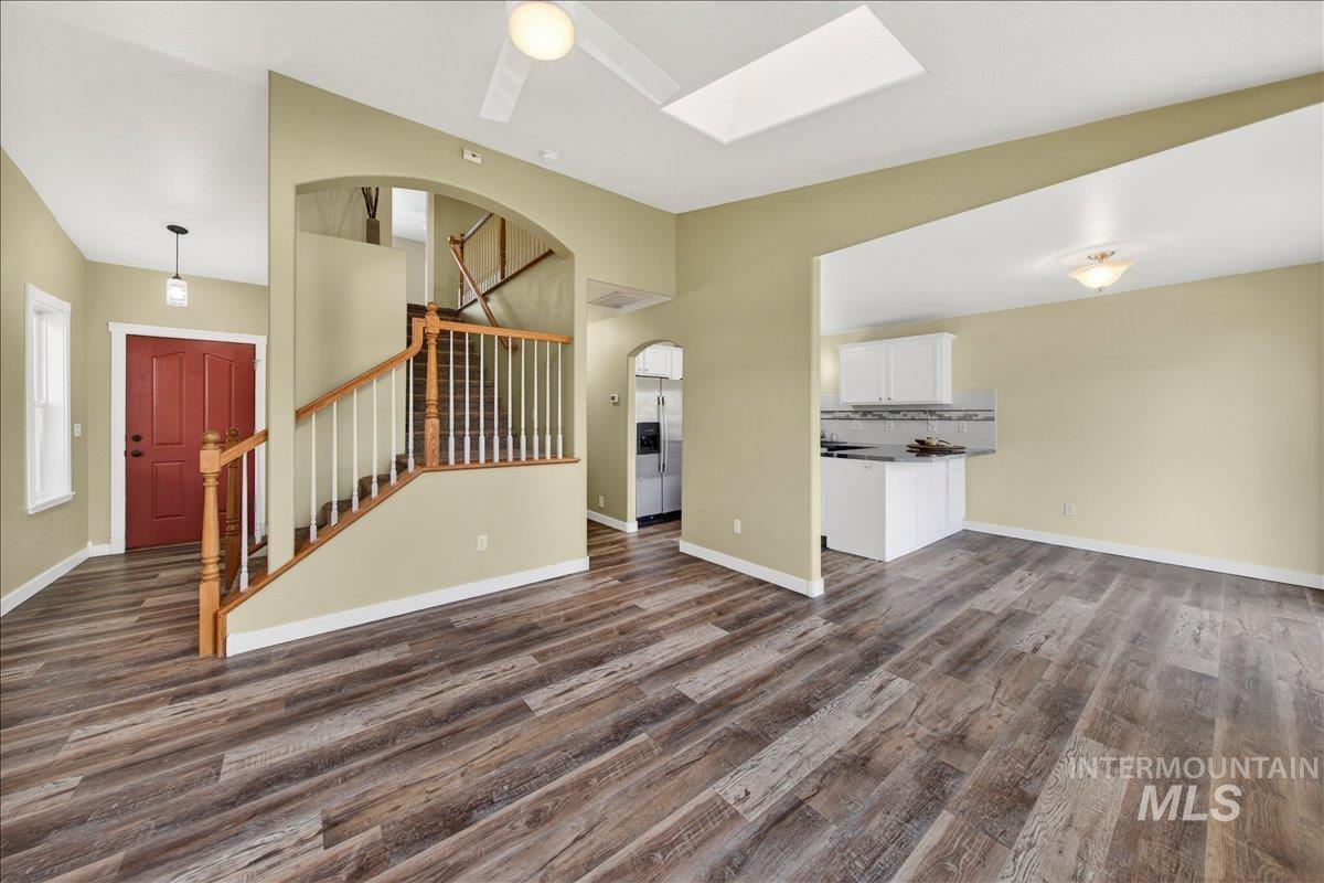 Unfurnished living room with dark wood-type flooring and a skylight