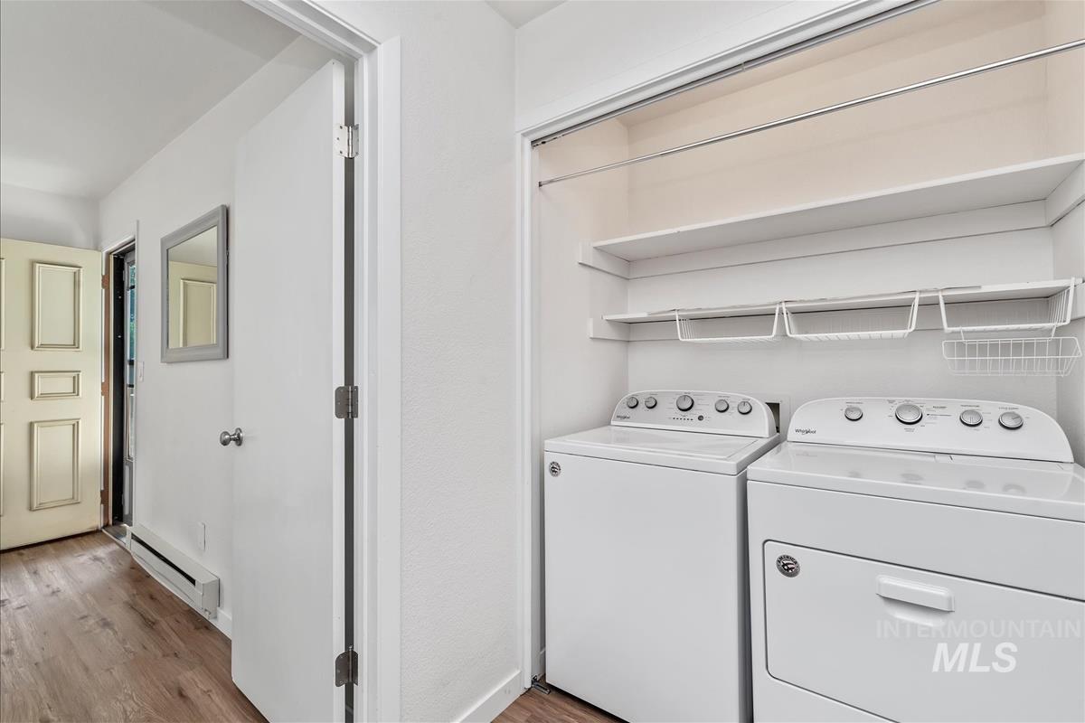 Laundry area with light wood finished floors, a baseboard radiator, and washing machine and clothes dryer