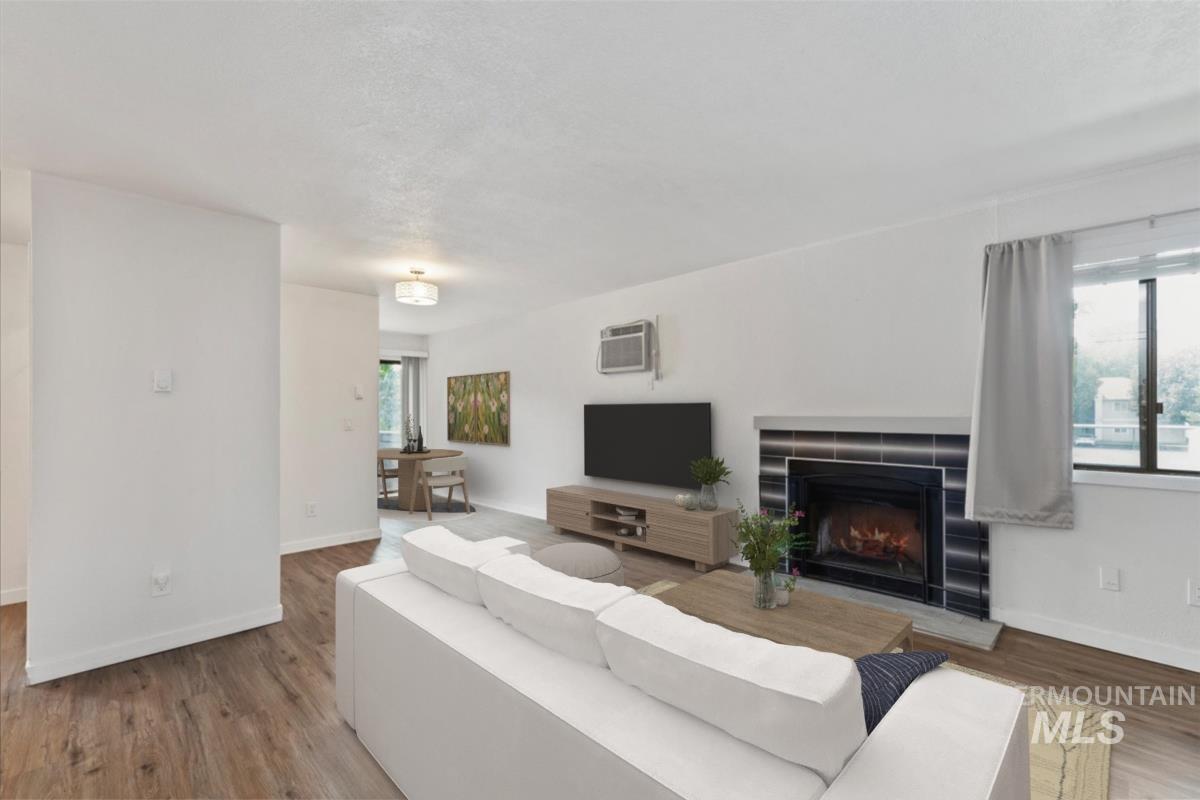 Living area featuring wood finished floors, a tiled fireplace, and healthy amount of natural light