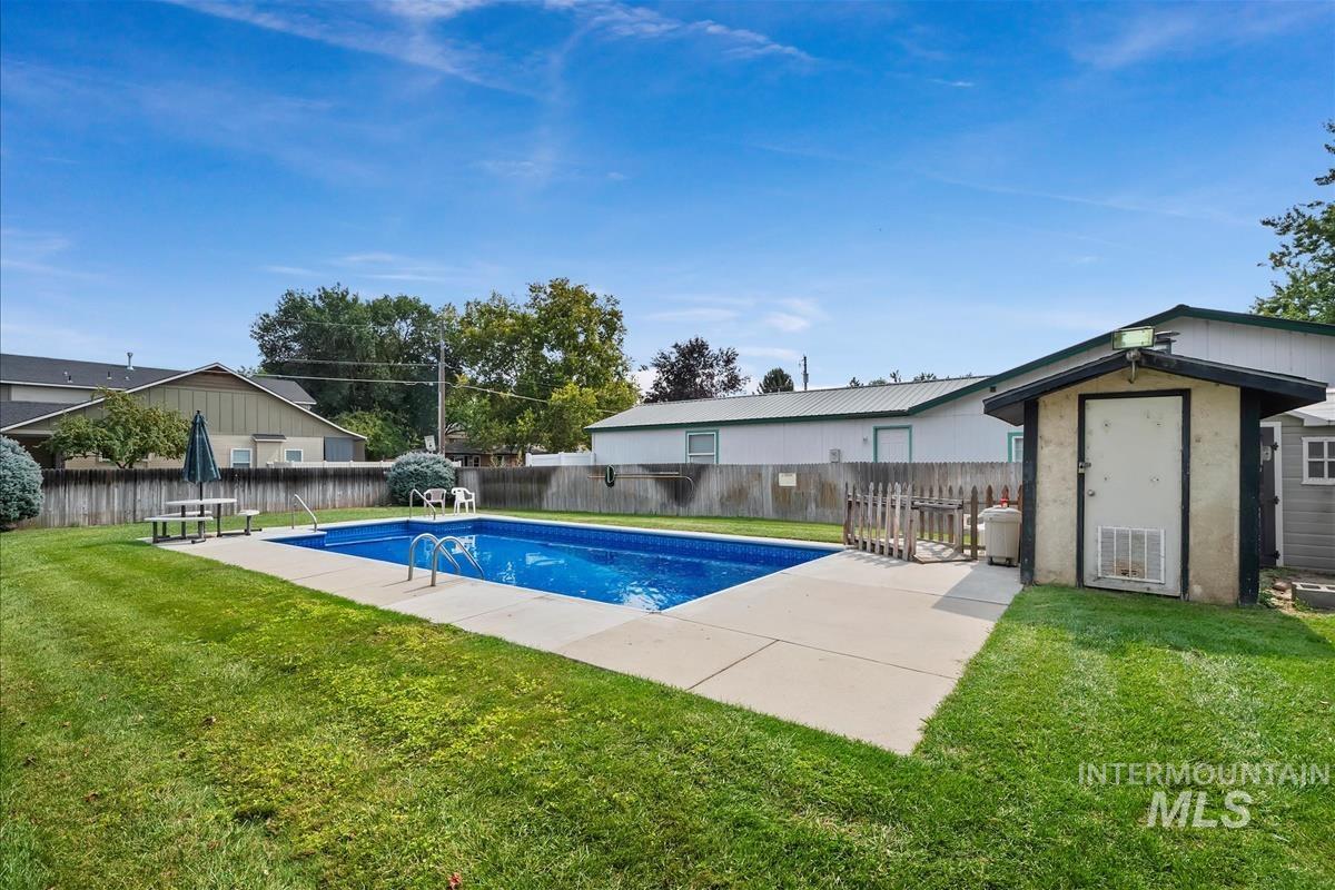 View of pool featuring a fenced backyard, patio surround, and a storage shed