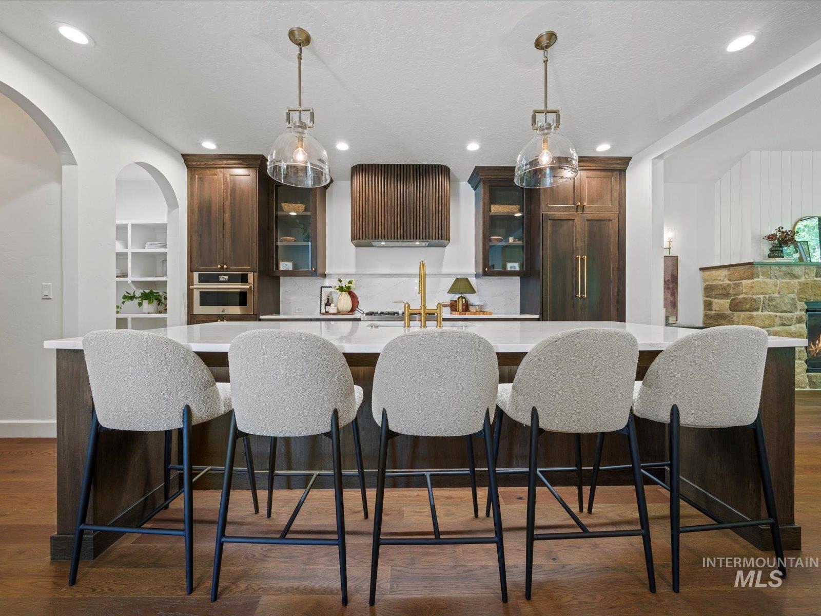 Kitchen with a kitchen breakfast bar, dark brown cabinetry, dark wood-style floors, hanging light fixtures, and recessed lighting