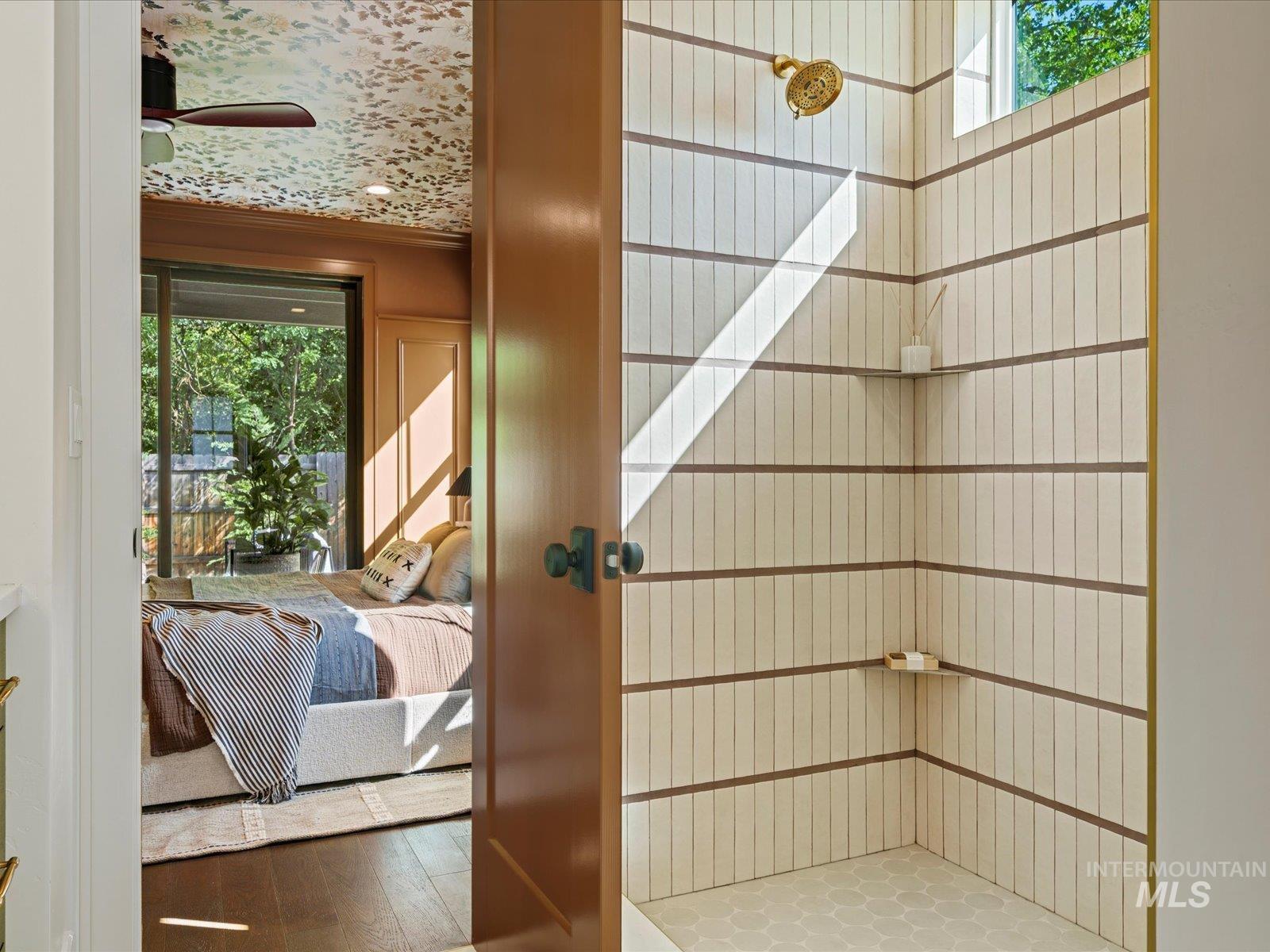 Interior space featuring a tile shower, wood finished floors, connected bathroom, and crown molding