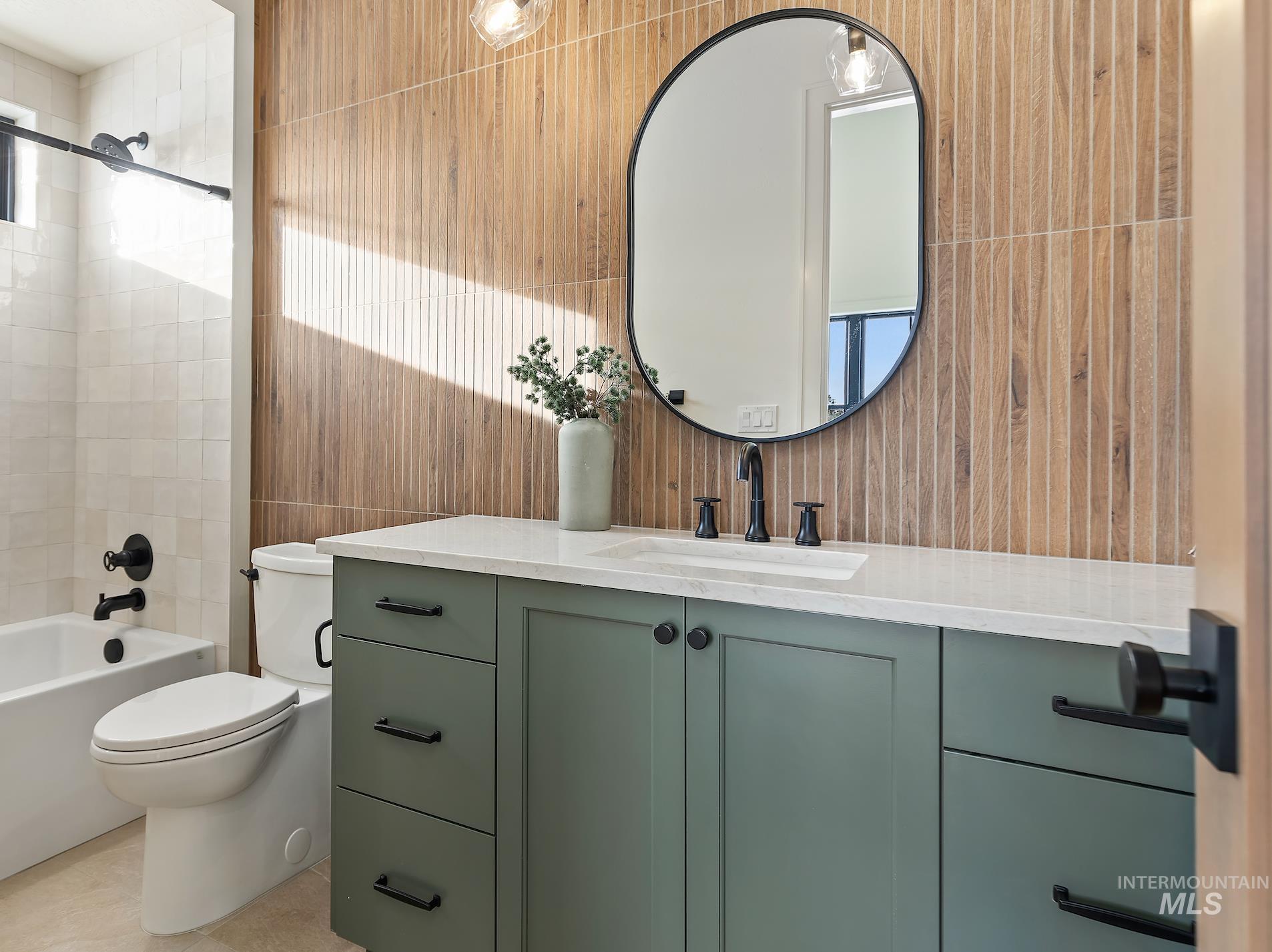 Bathroom featuring vanity, shower / bathtub combination, tile walls, and light tile patterned floors