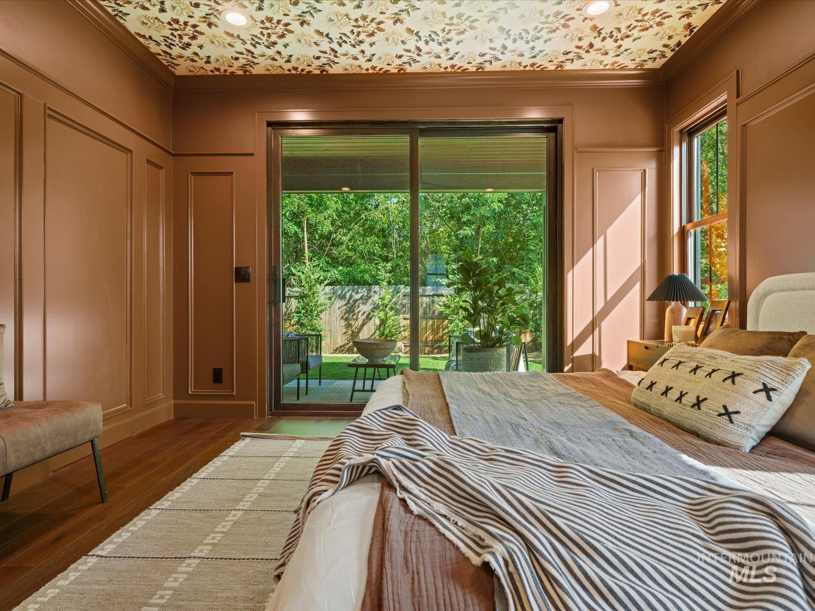 Bedroom with crown molding, access to outside, wood finished floors, and a decorative wall