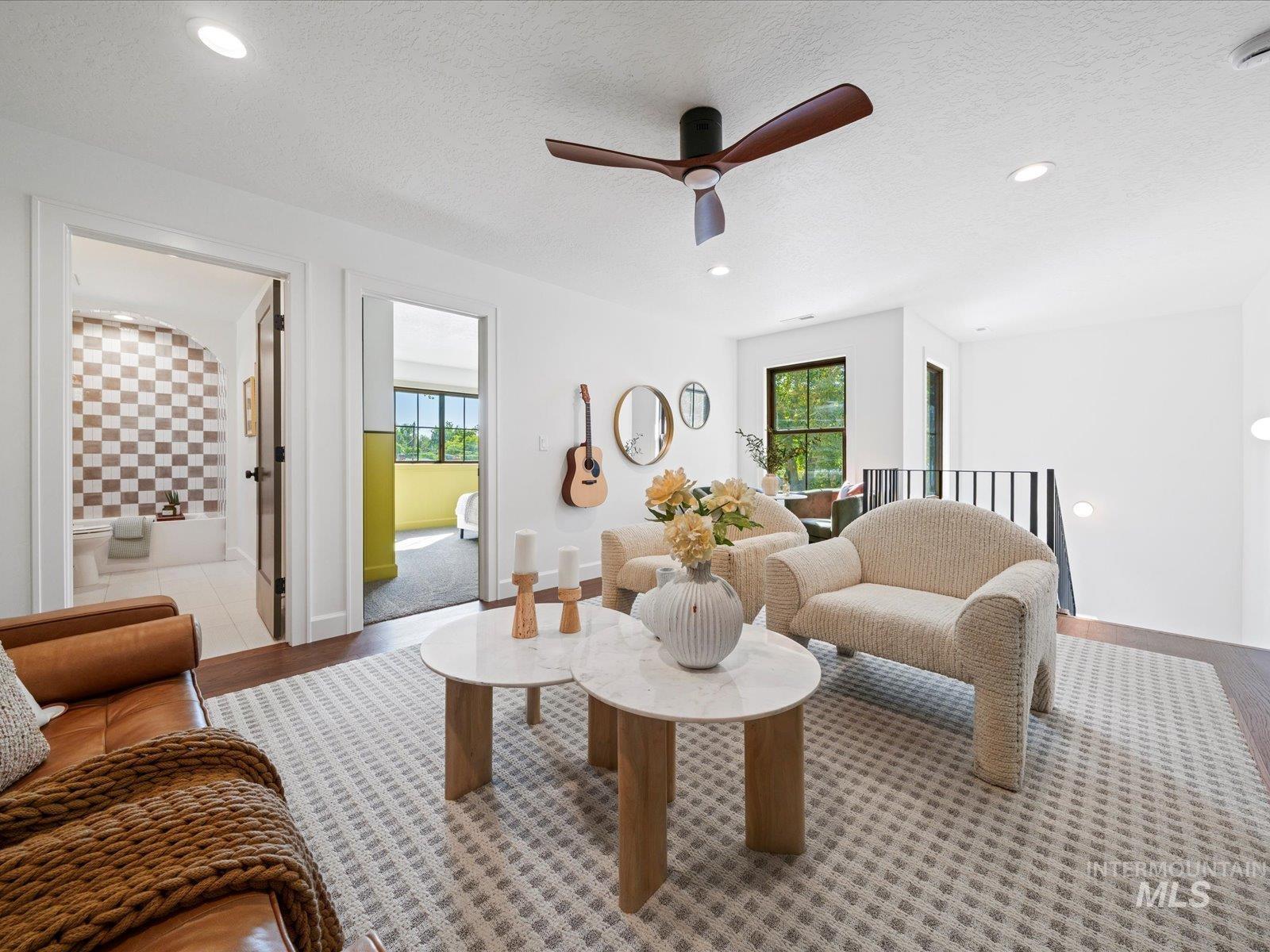 Living area with a textured ceiling, ceiling fan, recessed lighting, and wood finished floors