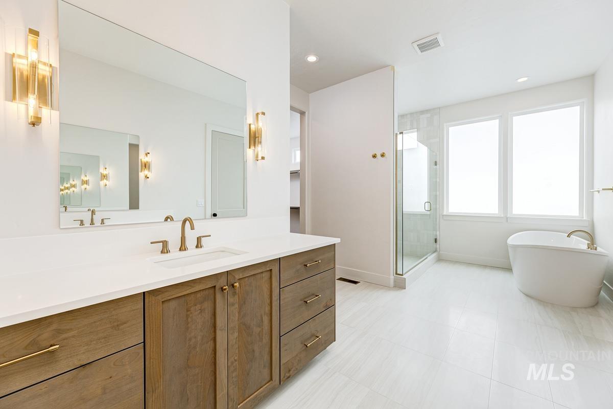 Bathroom featuring vanity, a stall shower, a freestanding tub, and recessed lighting