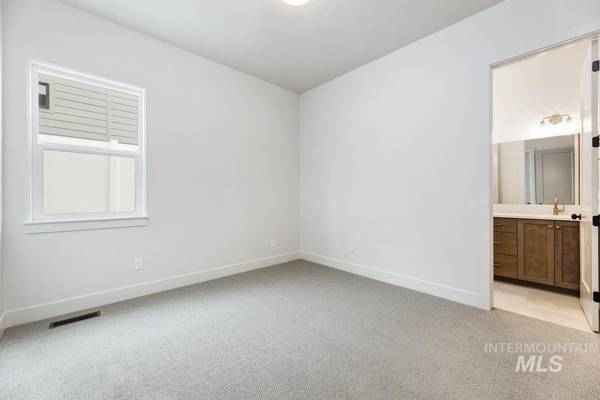 Unfurnished bedroom with light colored carpet and ensuite bath
