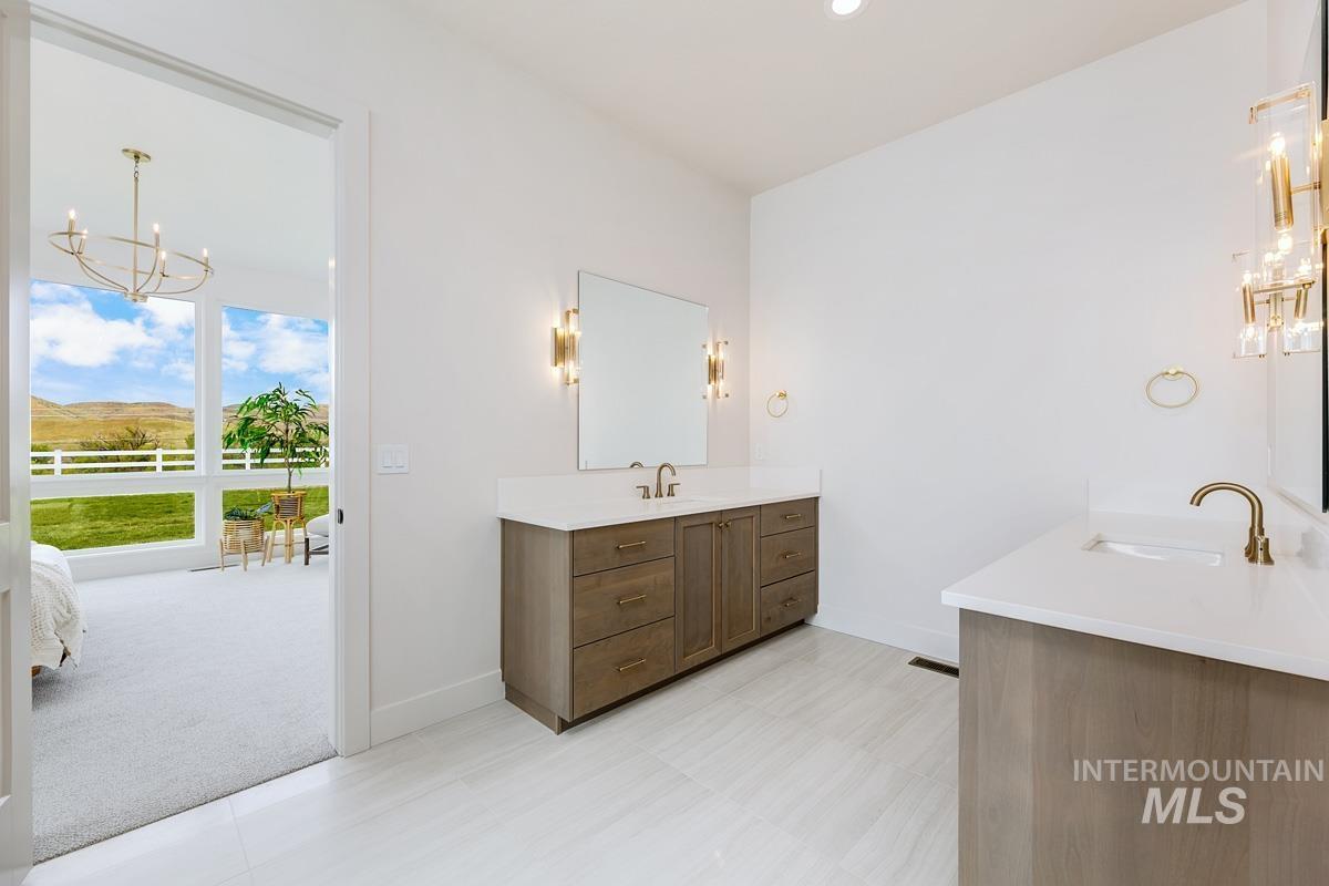 Bathroom featuring a chandelier, two vanities, connected bathroom, and recessed lighting