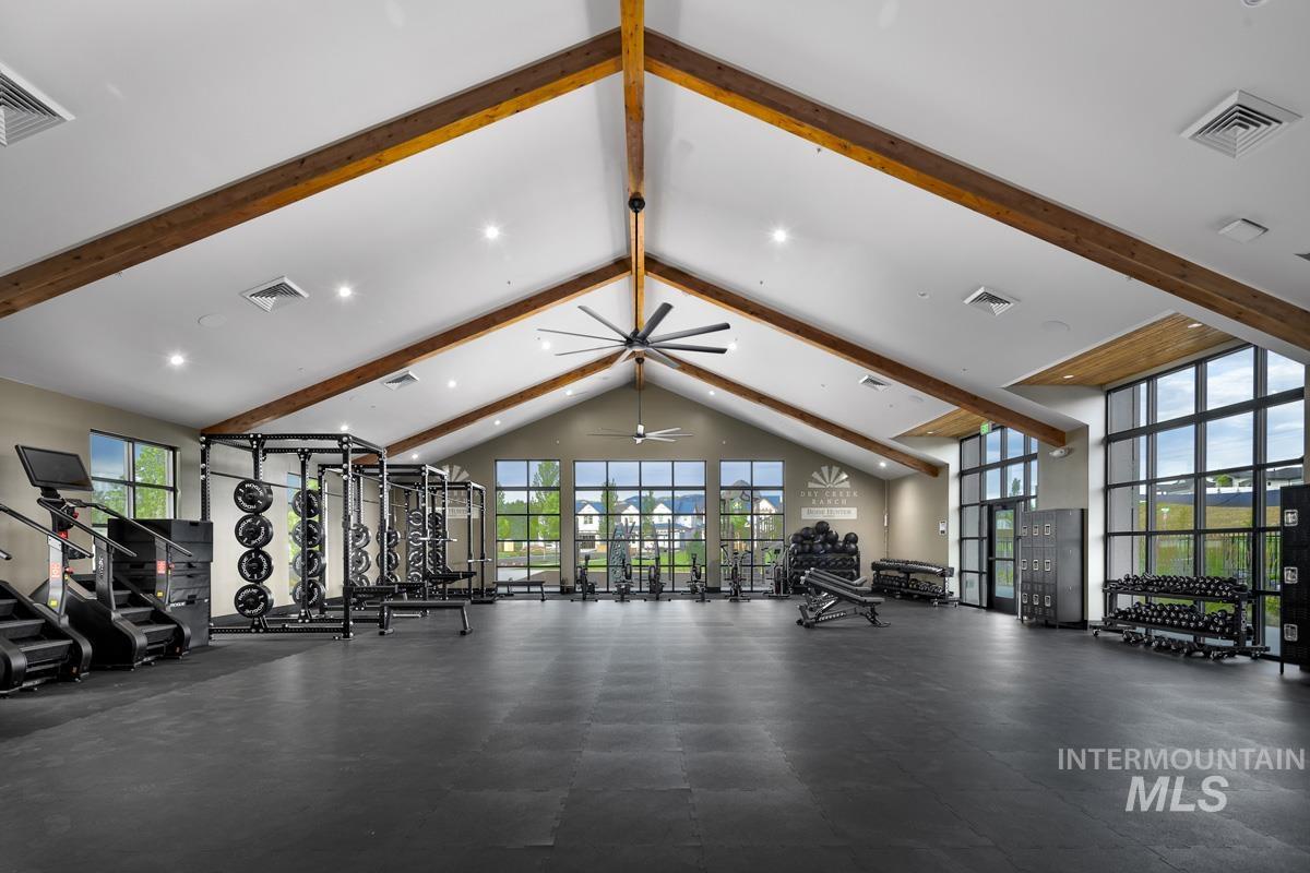Gym with healthy amount of natural light, beamed ceiling, a ceiling fan, and high vaulted ceiling