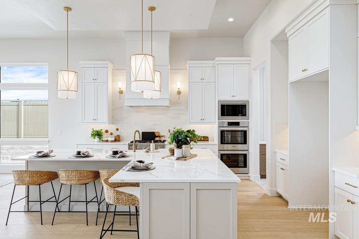 Kitchen featuring white cabinets, a kitchen bar, light wood-style floors, decorative light fixtures, and recessed lighting