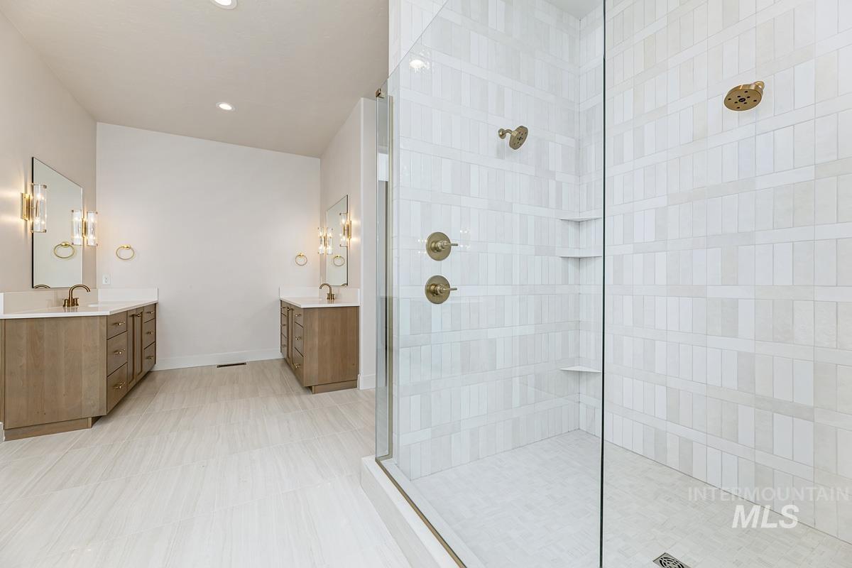 Bathroom with walk in shower, two vanities, and recessed lighting