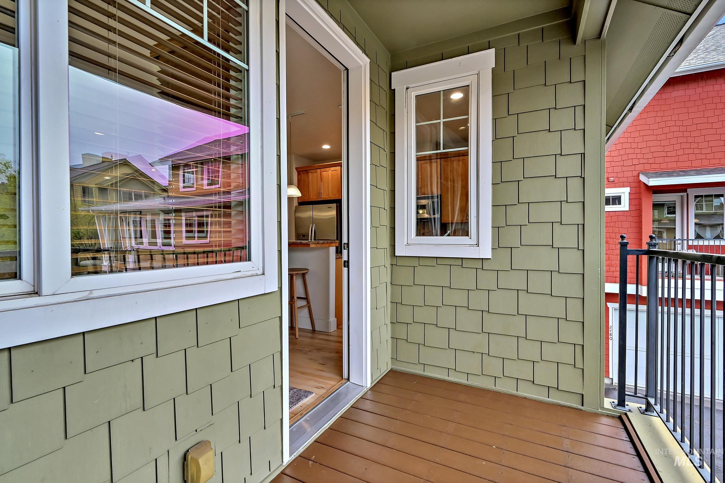 Covered deck with railing and neighborhood views. Comfortable outdoor space for relaxing.