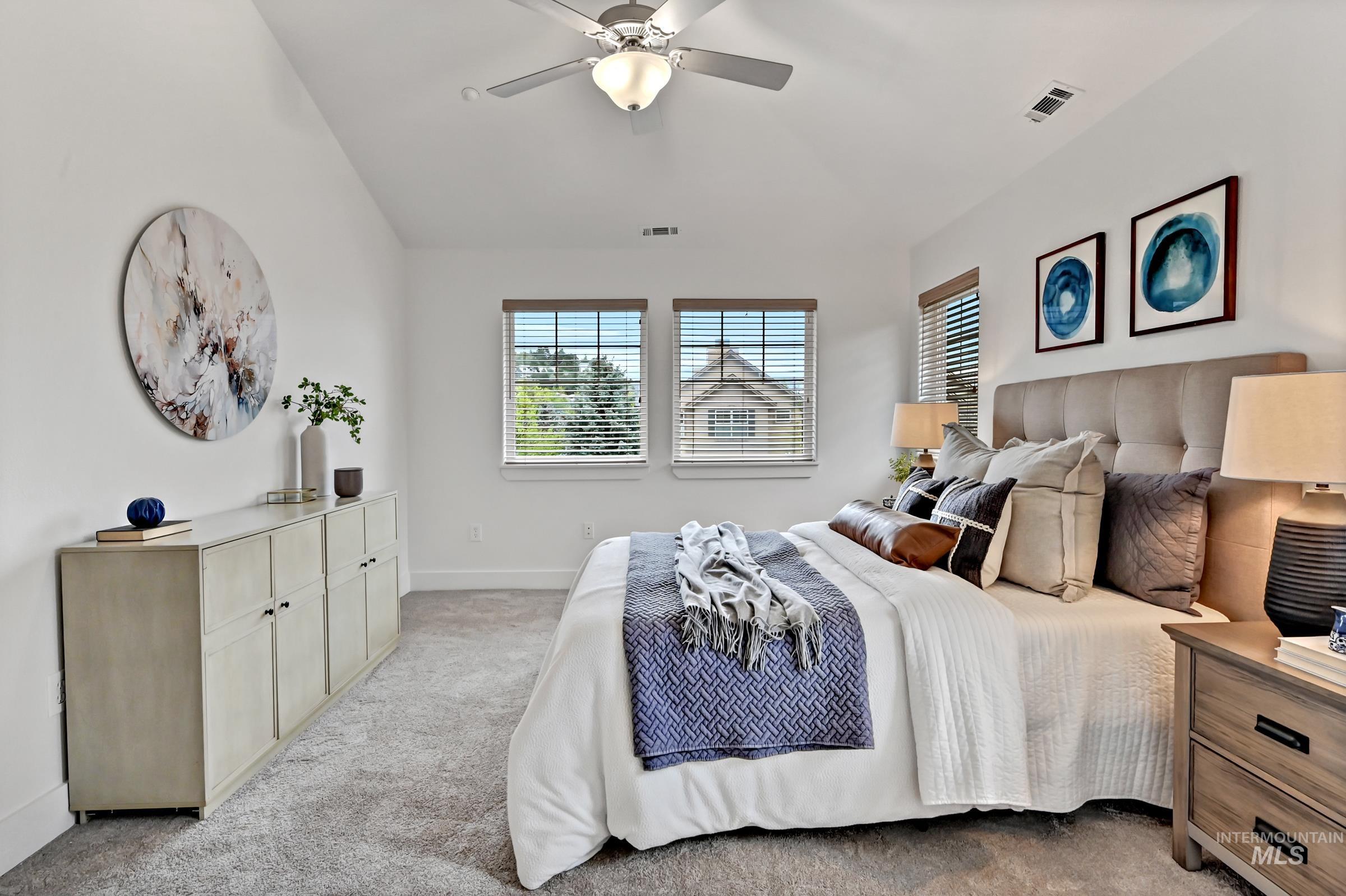 Primary ensuite bedroom with carpet, ceiling fan, and neutral tones. Bright and comfortable space.