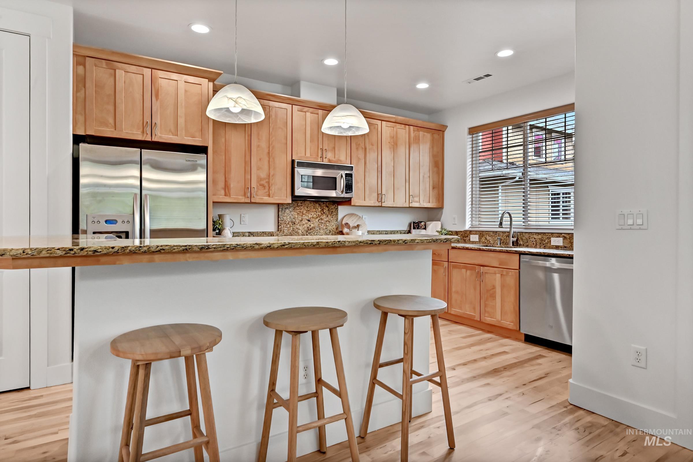 Kitchen with granite counters, island seating, and pantry storage. Functional layout with warm cabinetry and good light.