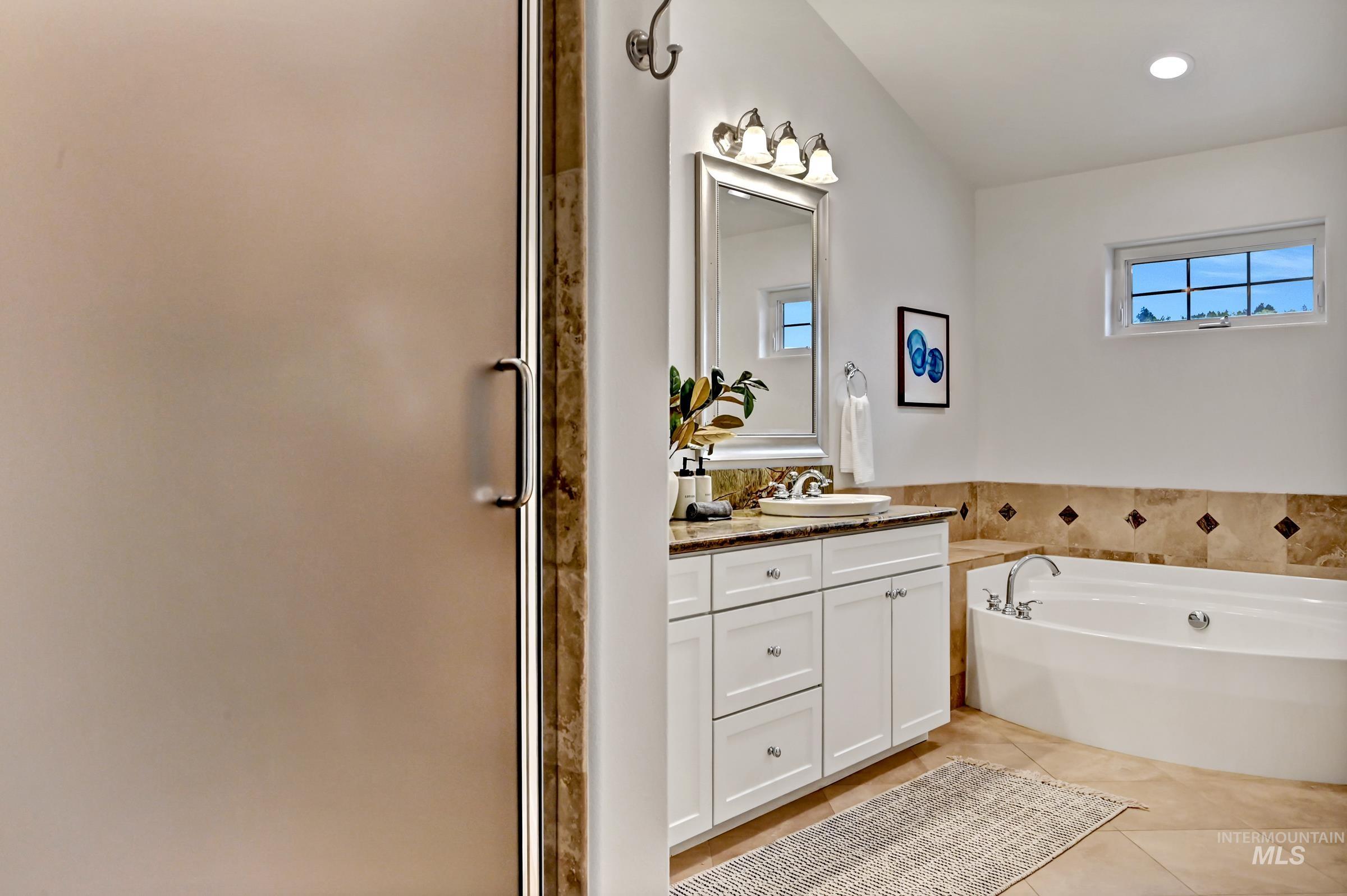 Ensuite bathroom with dual vanities, large mirrors, a soaker tub, walk-in shower, and updated finishes. Clean, functional layout with good lighting.