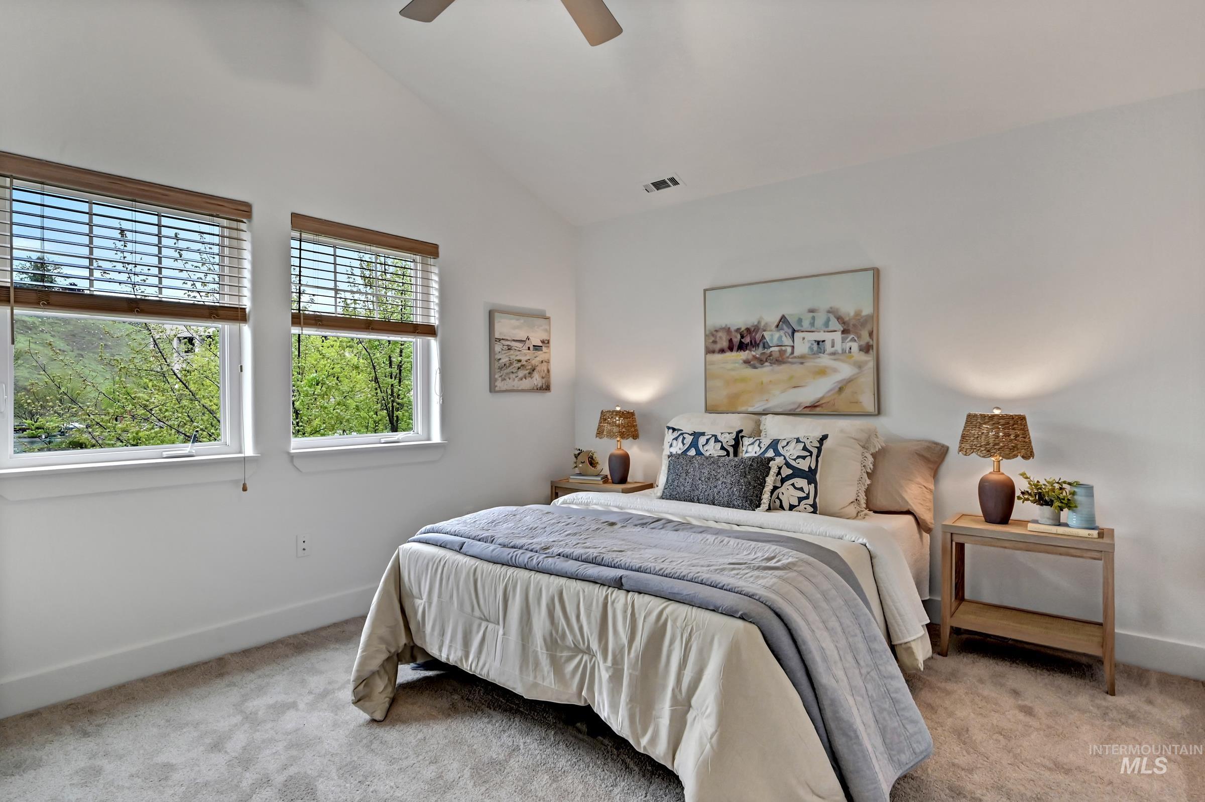 Ensuite bedroom with large window and carpeting. Bright space with neutral finishes.