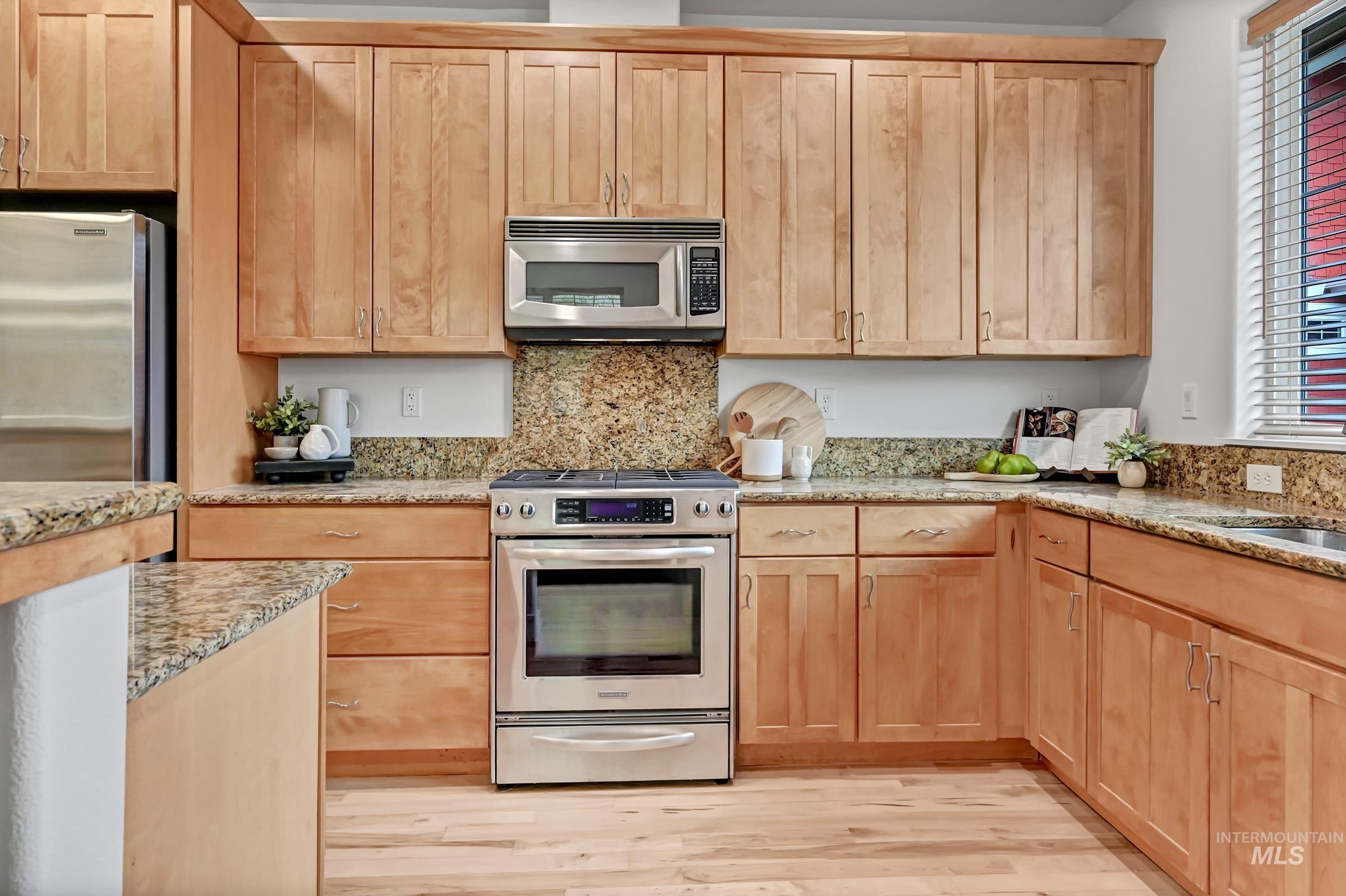 Kitchen with wood cabinets, granite counters, and stainless appliances. Efficient layout with an island and large windows.
