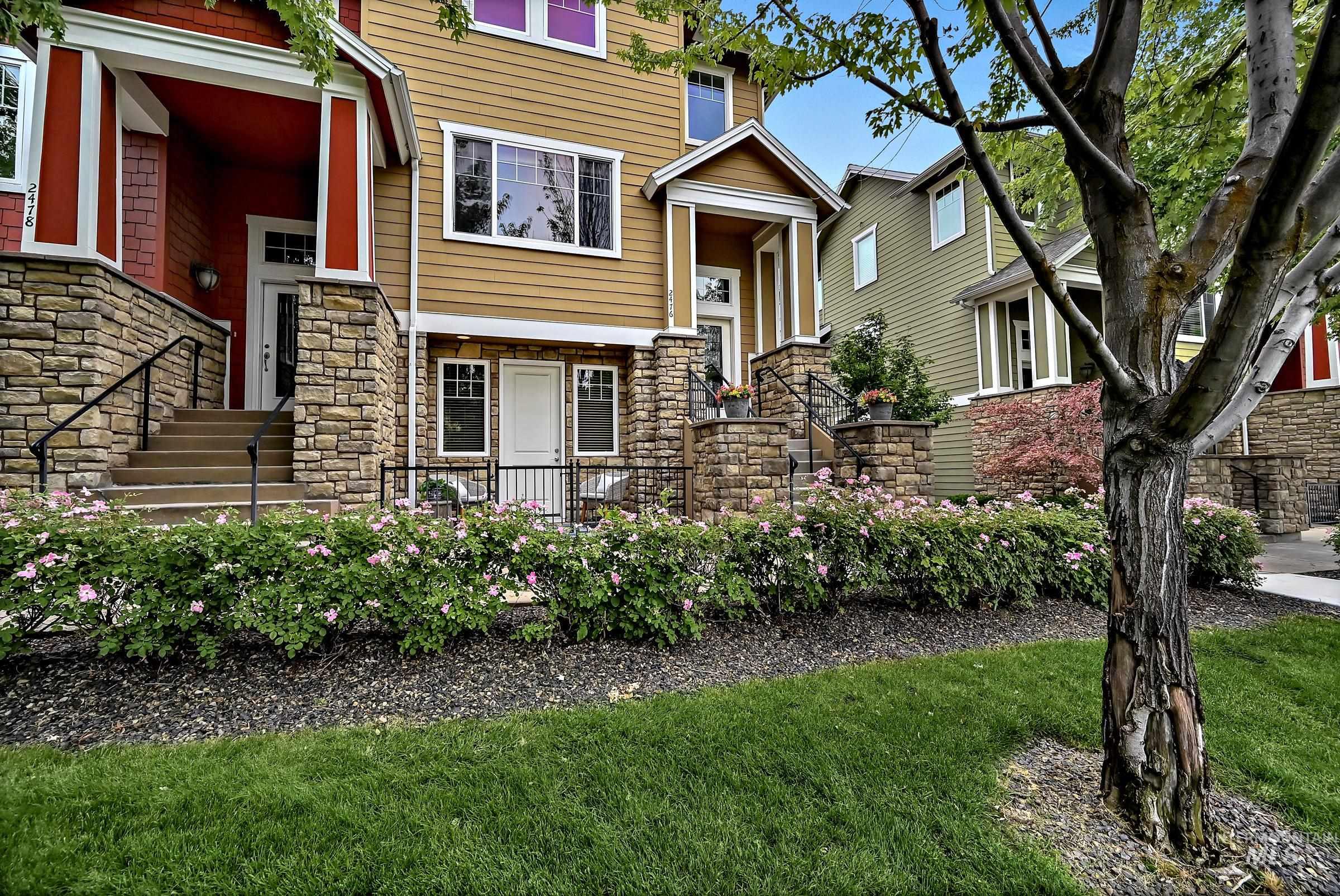 Multi-level townhome exterior featuring stone accents and a covered entry