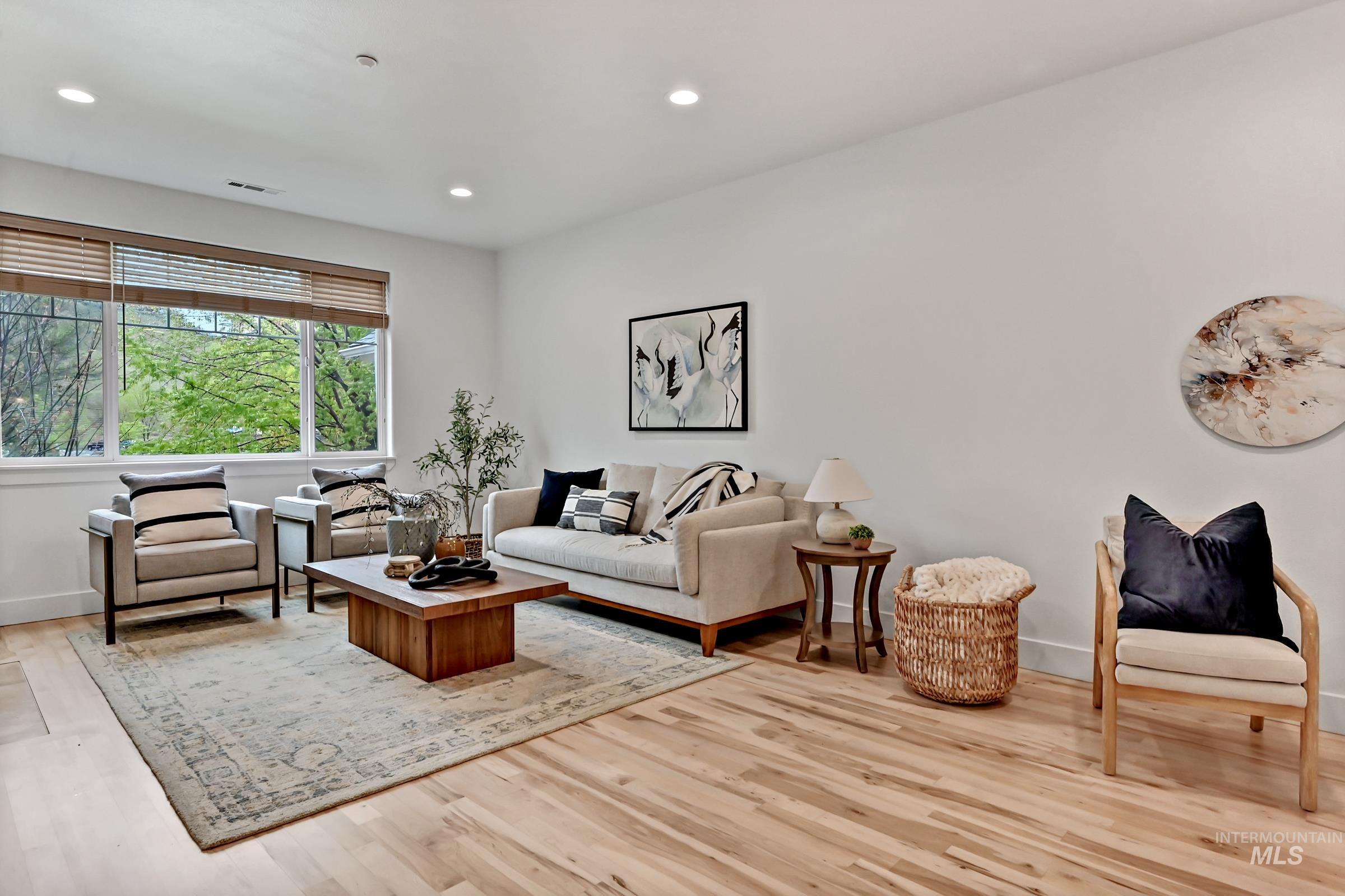 Living area with newly refinished hardwood flooring, fireplace, and large windows. Bright, open feel.