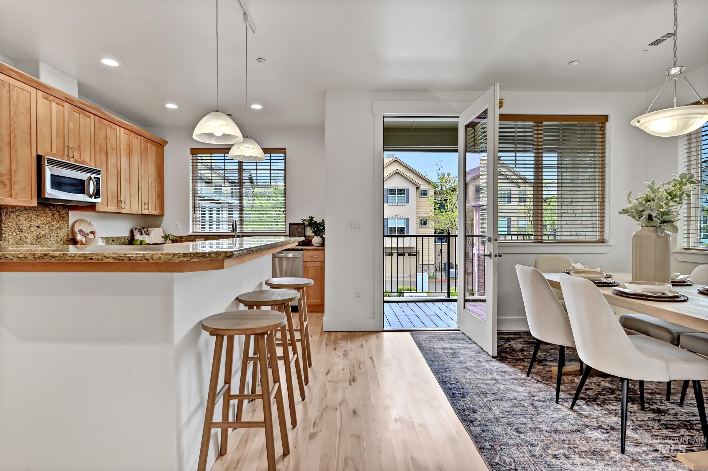 Kitchen and dining area with wood cabinetry, island seating, and access to outdoor space. Open and inviting layout.