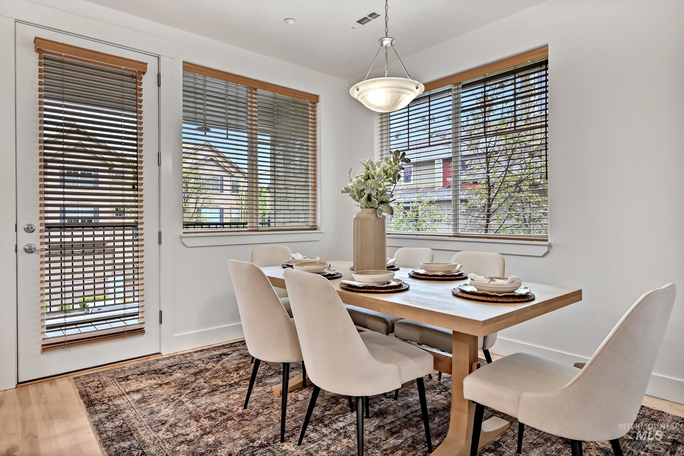 Dining area with large windows and access to covered outdoor space. Bright setting with hardwood floors.