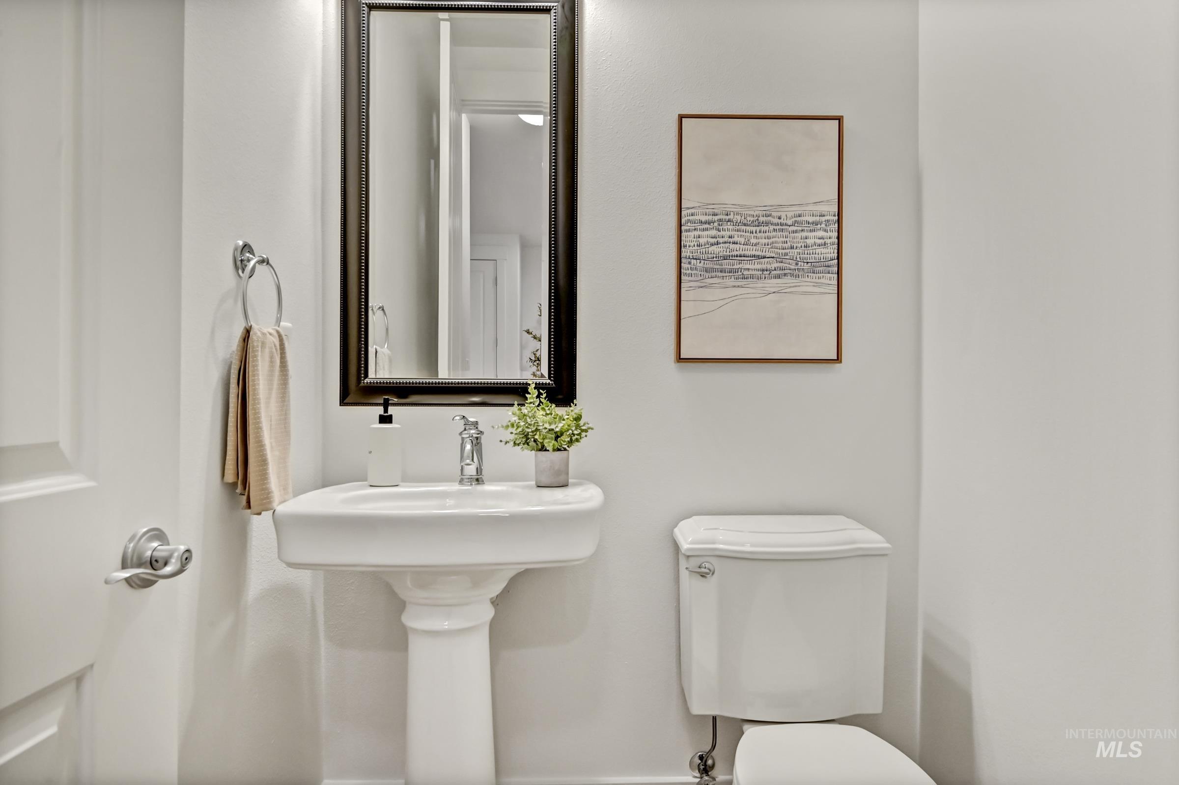 Main level half bathroom with pedestal sink and mirror. Clean and compact layout.