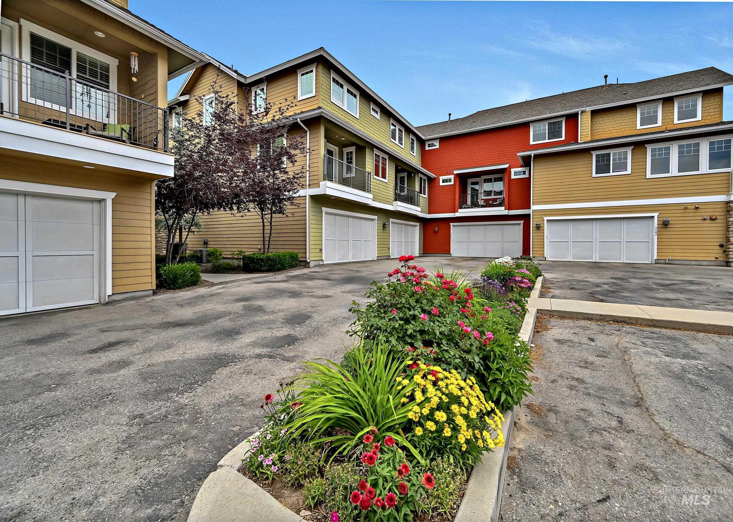 Well-kept rear parking area with garage access. Sidewalk to front of building with mature landscaping.