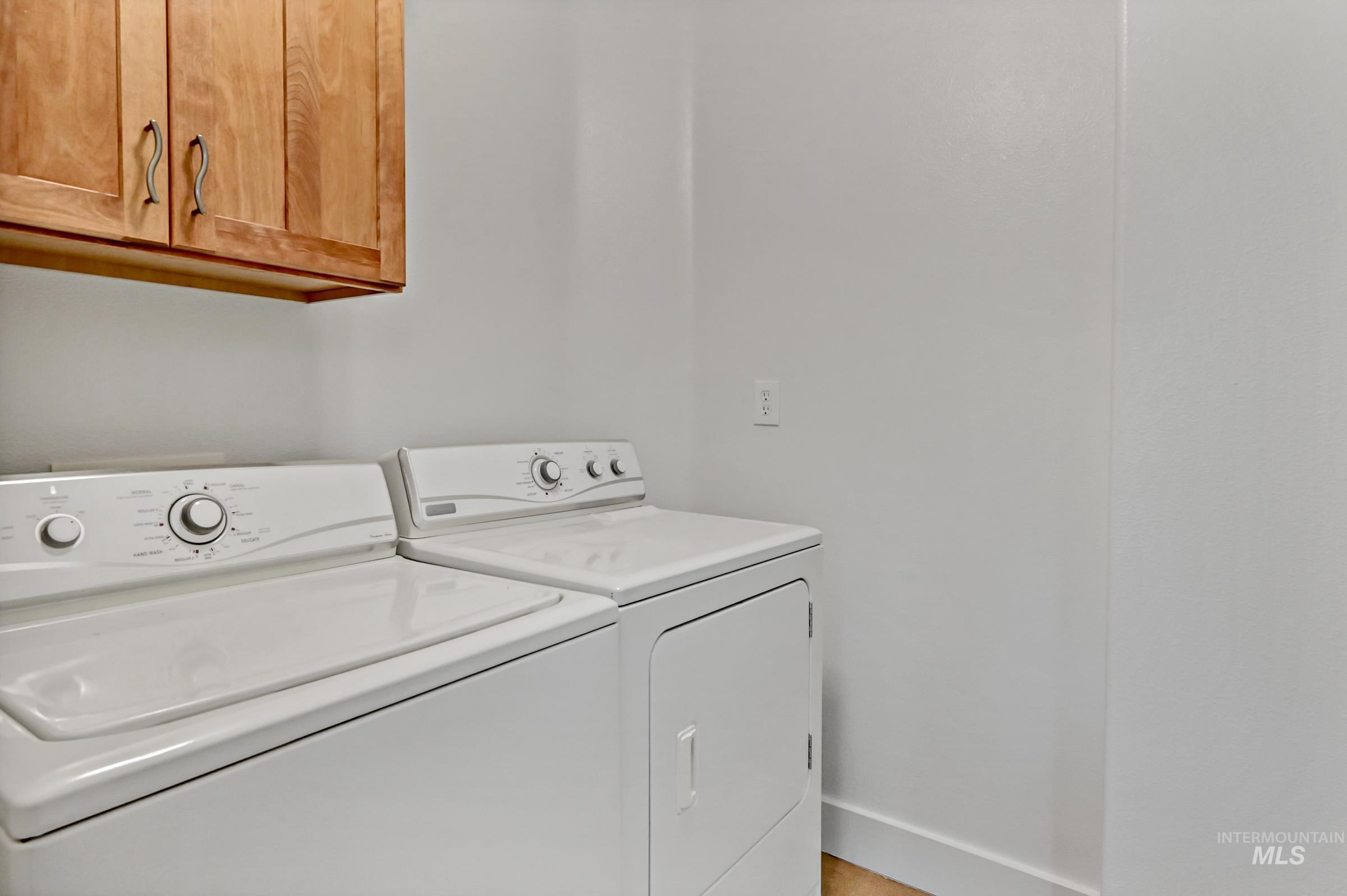 Upstairs laundry room with wood cabinets, and a washer and dryer. Convenient and practical setup.