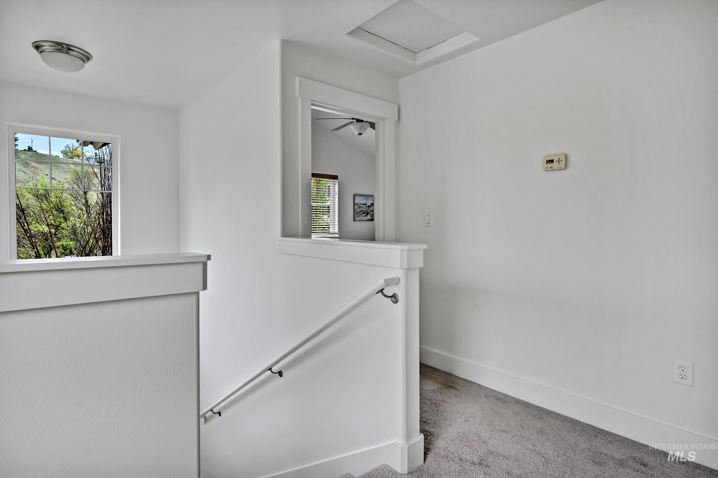 Stair landing and hallway with large windows and doors to both ensuites and the laundry room.