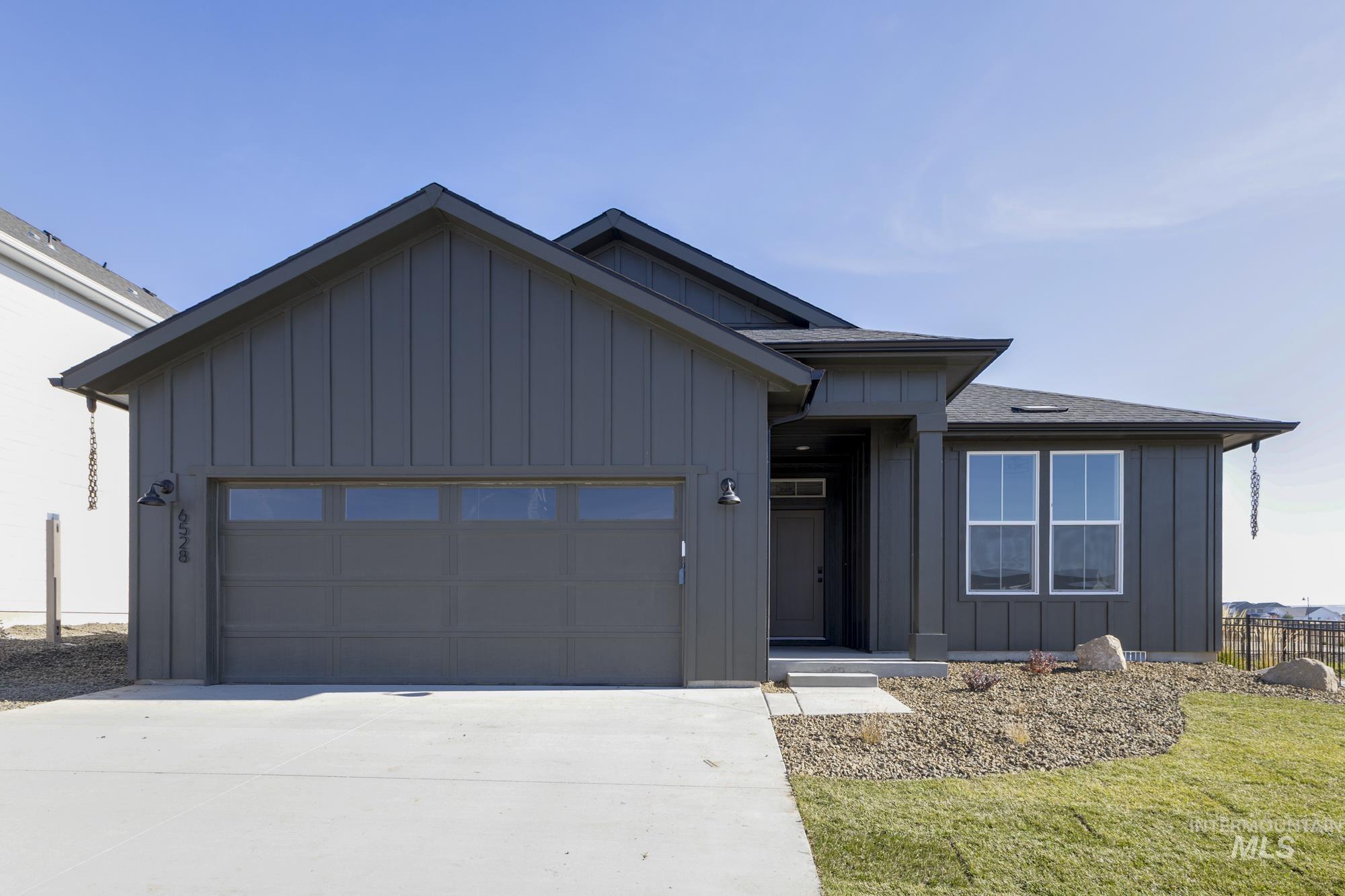 View of front of home with board and batten siding, an attached garage, and concrete driveway