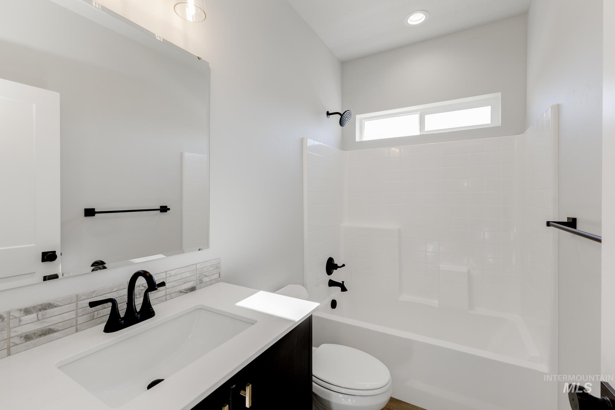Full bath with vanity, shower / bath combination, and backsplash
