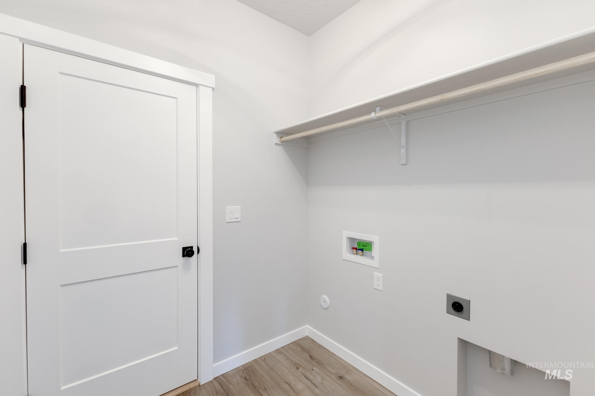 Laundry area with hookup for a washing machine, light wood-type flooring, and electric dryer hookup