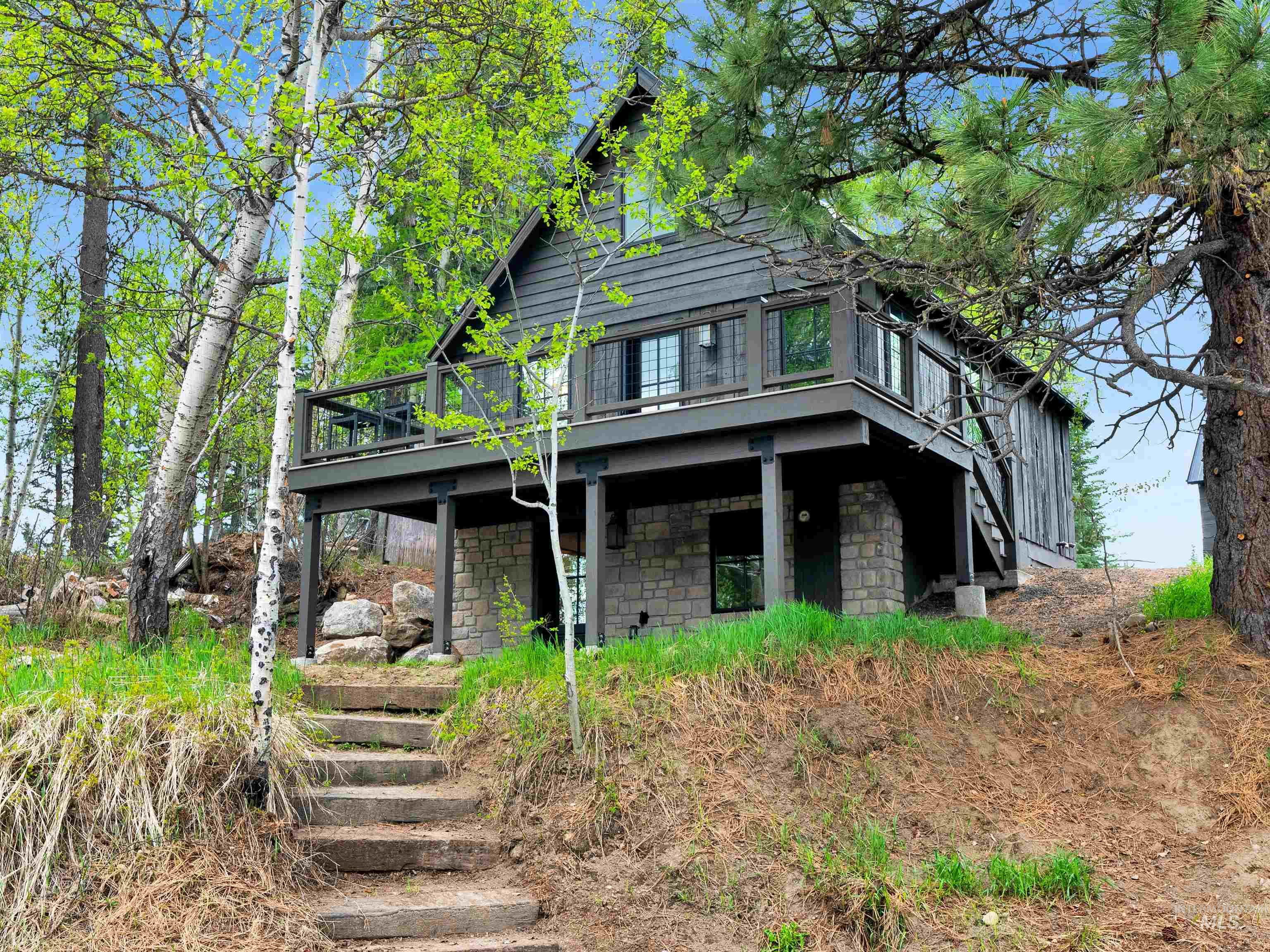 View of front facade with stone siding and a wooden deck