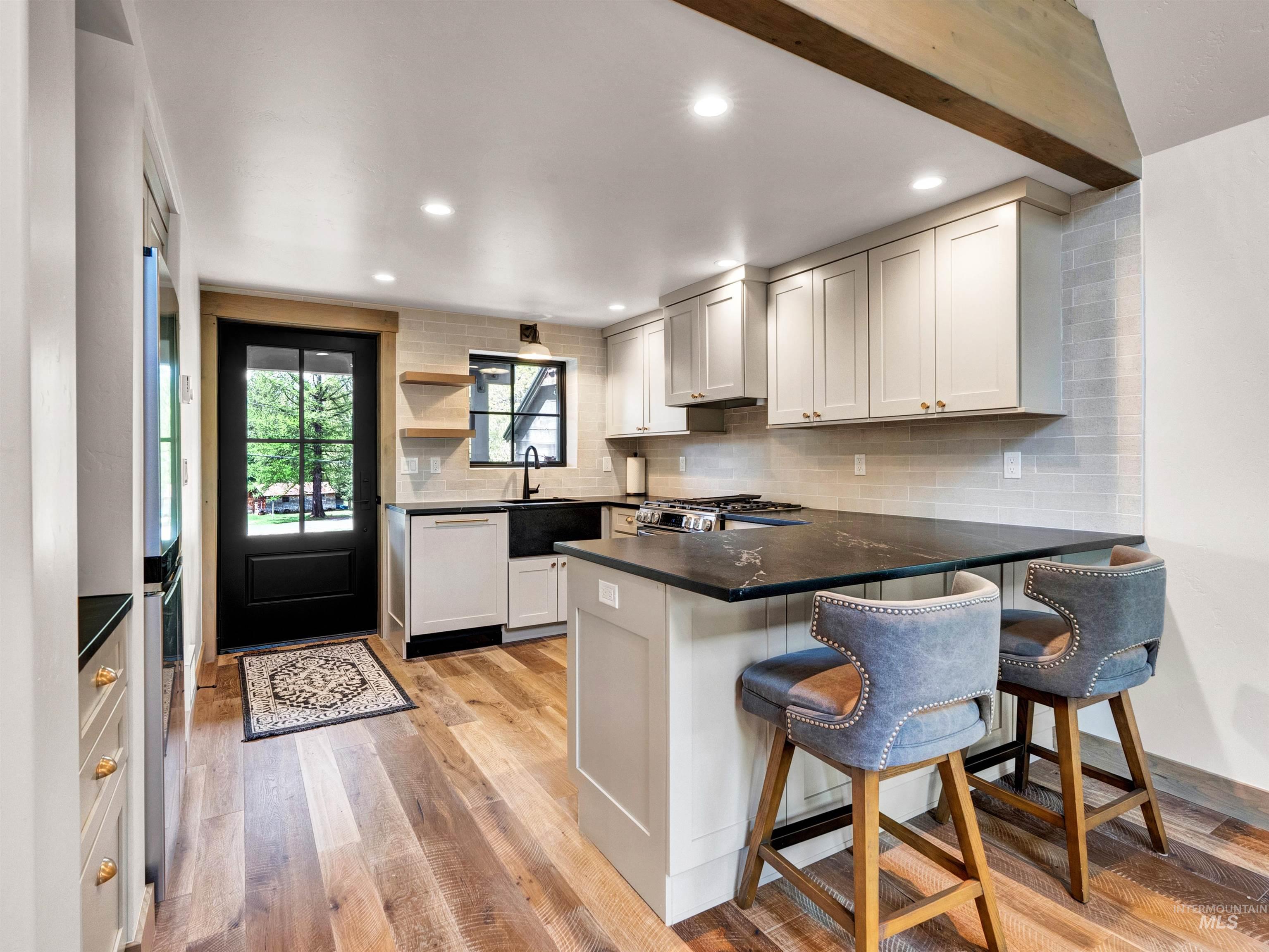 Kitchen featuring tasteful backsplash, light wood finished floors, open shelves, a peninsula, and dishwasher