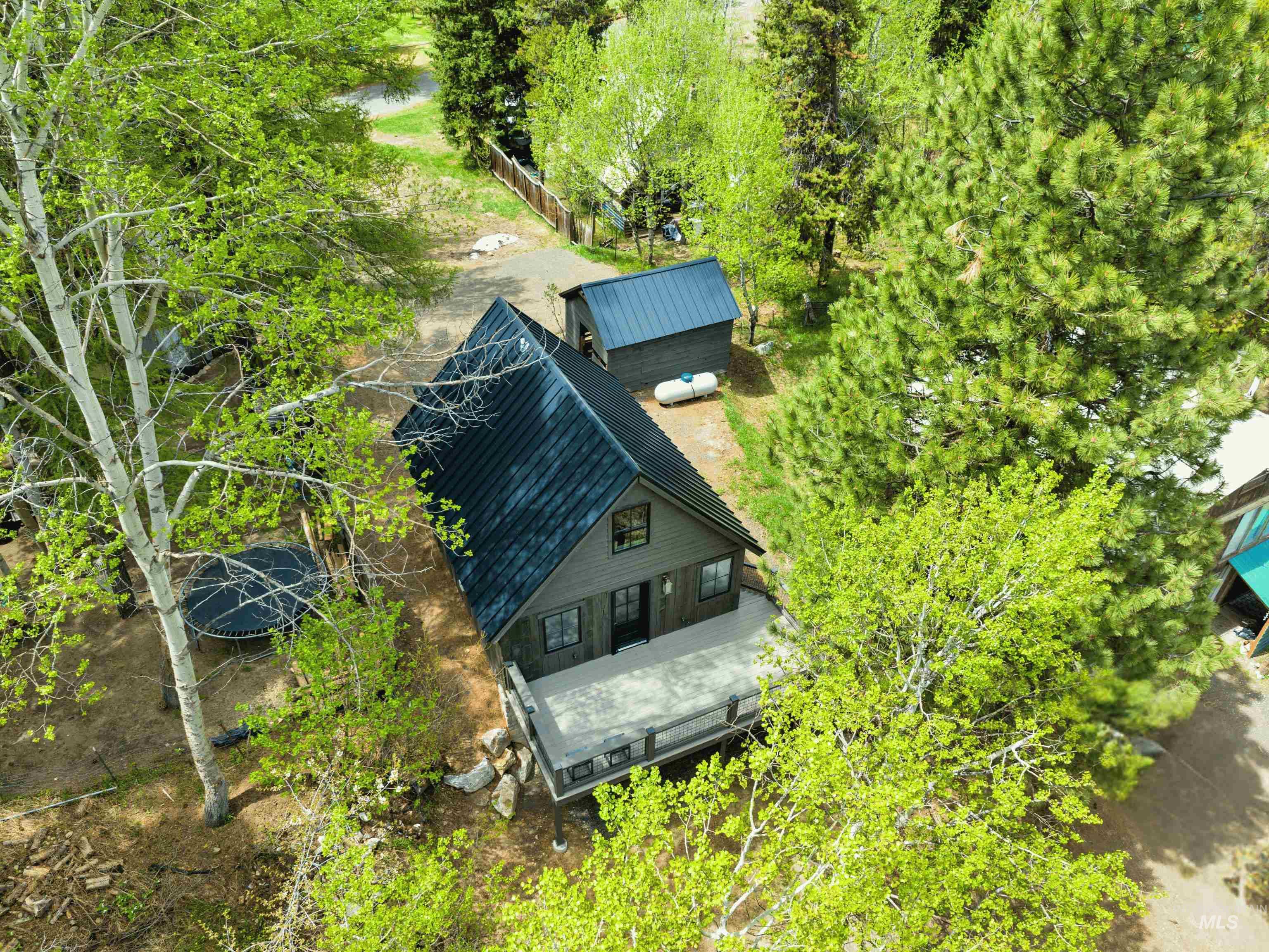 Aerial view of property and surrounding area featuring a tree filled landscape